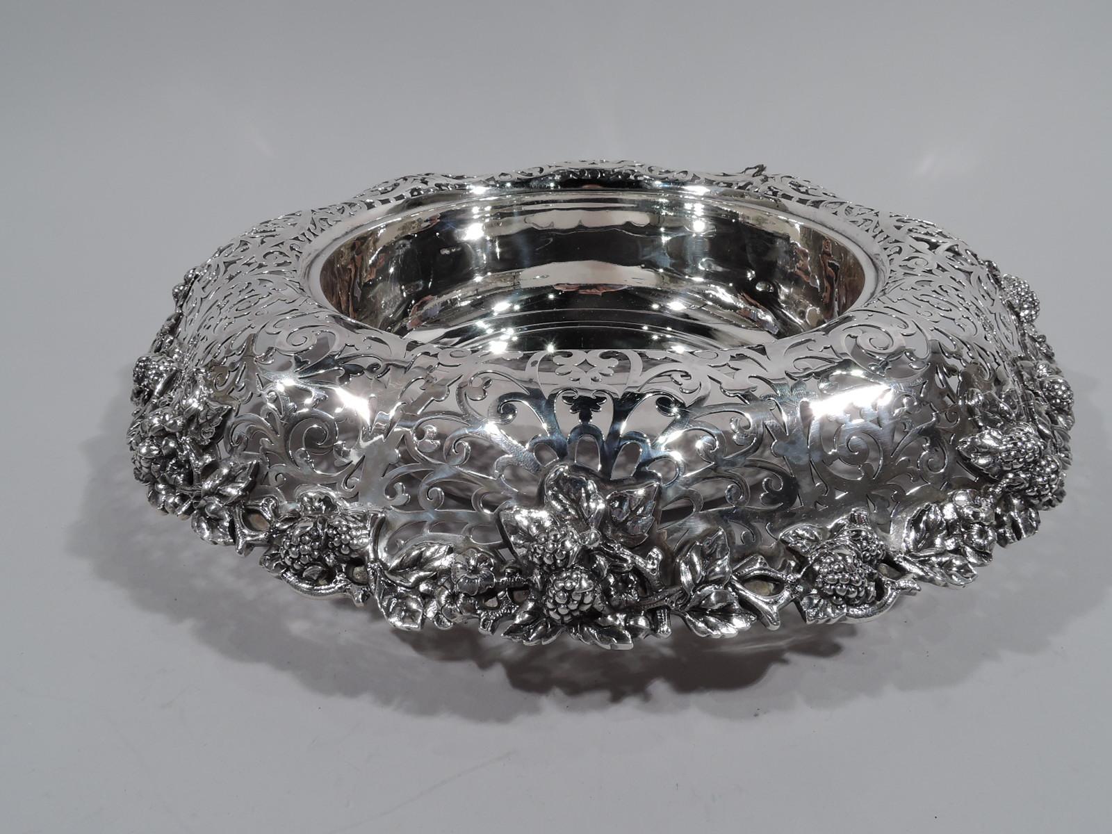 Small sterling silver centerpiece bowl. Made by Dominick & Haff in New York in 1888. Solid well with curved bottom and inset foot ring. Turned-down wavy shoulder with dense pierced scrollwork. Fruiting berry branch applied to rim. A great high-low