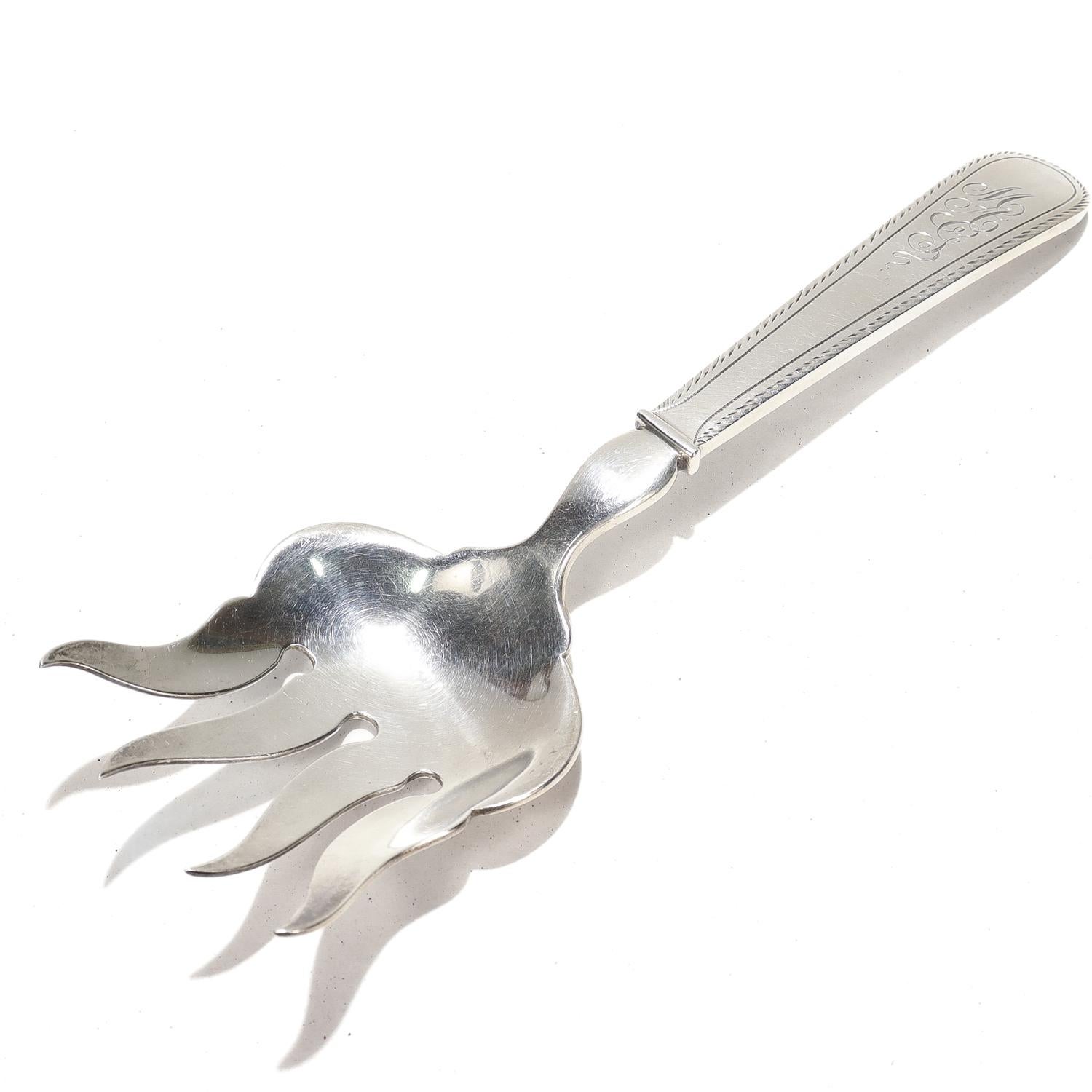 Un tenedor de servir americano antiguo.

En plata de ley muy robusta y de grueso calibre.

Fabricado por Dominick & Haff para Theodore B. Starr.

Con púas anchas y mango grueso.

Similar a los patrones Old English nº 1 y Martha Washington de