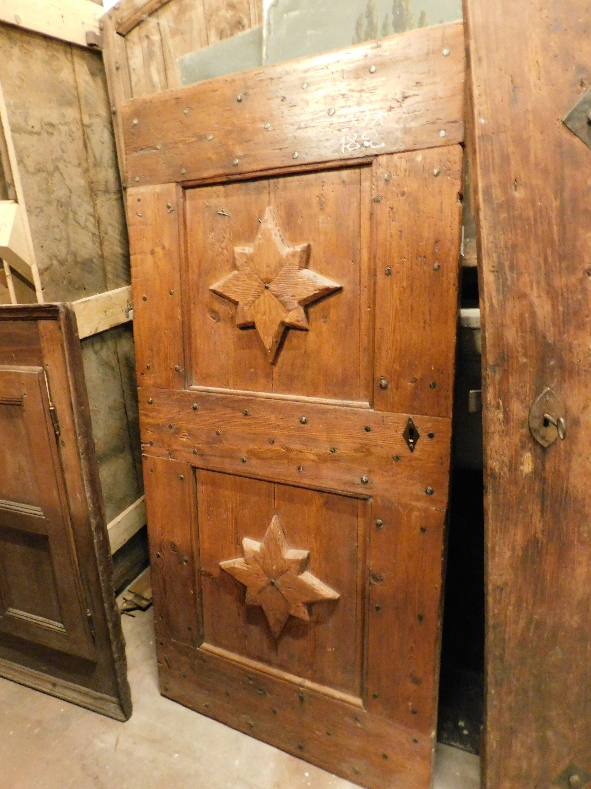 Ancient door in red larch wood, very charming color, has a hand carved star on the central panel, rustic and lived-in look, beautiful patina of a door that has lived the high mountains, coming from a hut in Italy, built in the late period