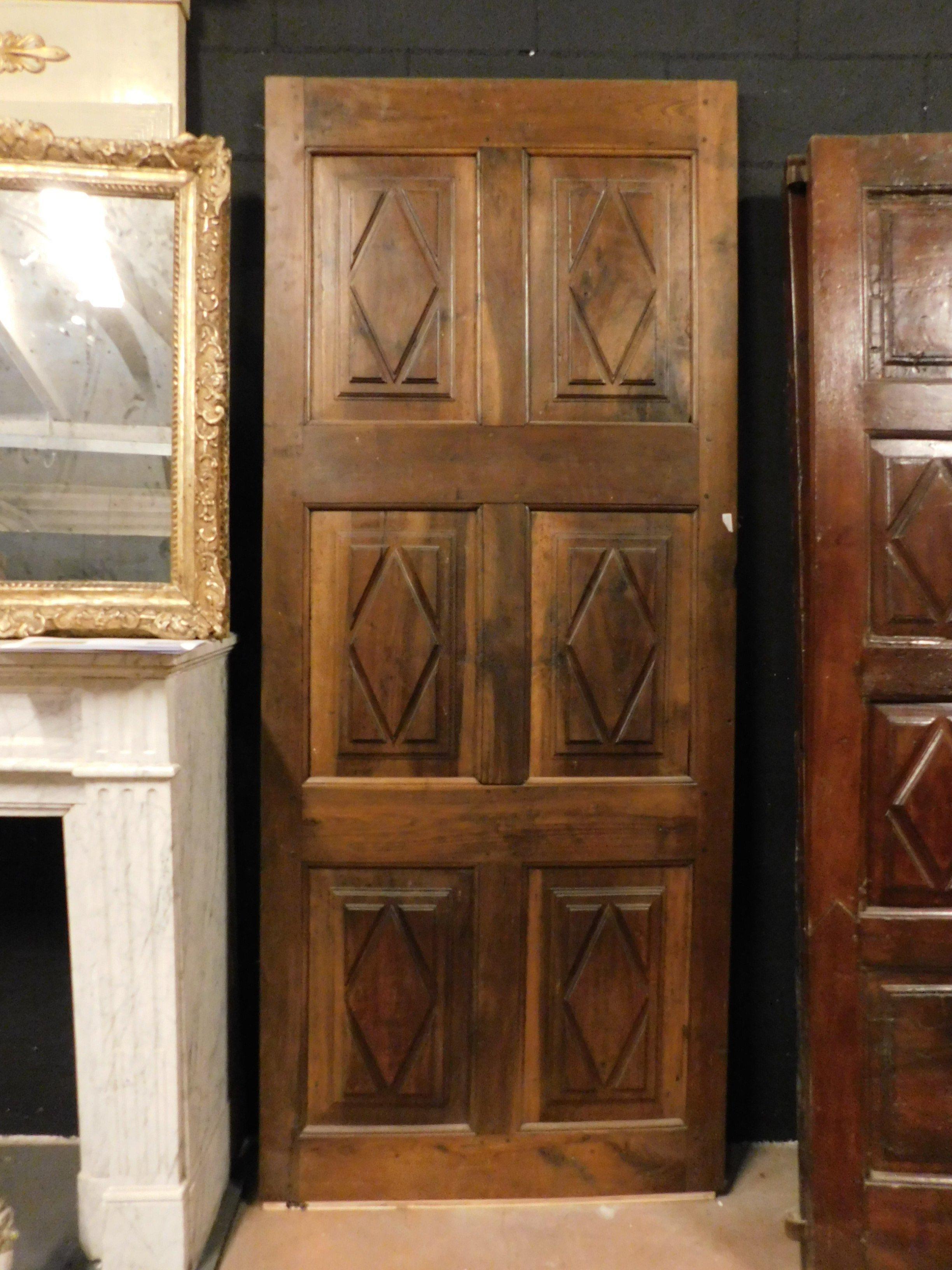 Antique interior door in solid walnut brown wood, patinated and hand-sculpted with lozenges, built in the 18th century for a building in the historic center of northern Italy (from Piedmont), to be installed directly on the wall, size cm w 90 x h