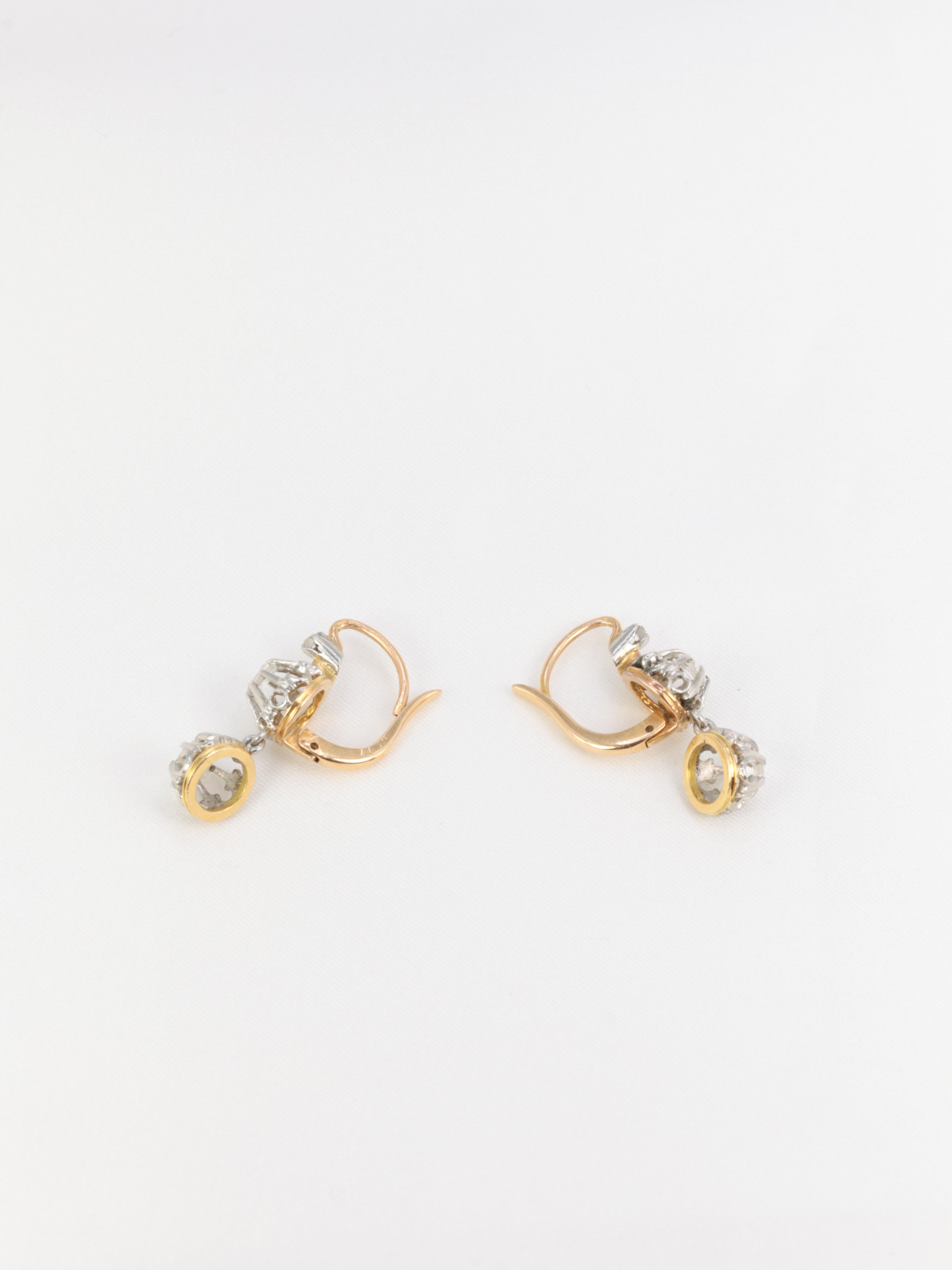 18Kt (750°/°°) yellow gold and silver dormeuse earrings featuring a small rose-cut diamond set in a larger, beautifully worked and openworked bezel. These earrings hold another bezel in pendeloque set with a rose-cut diamond of comparable