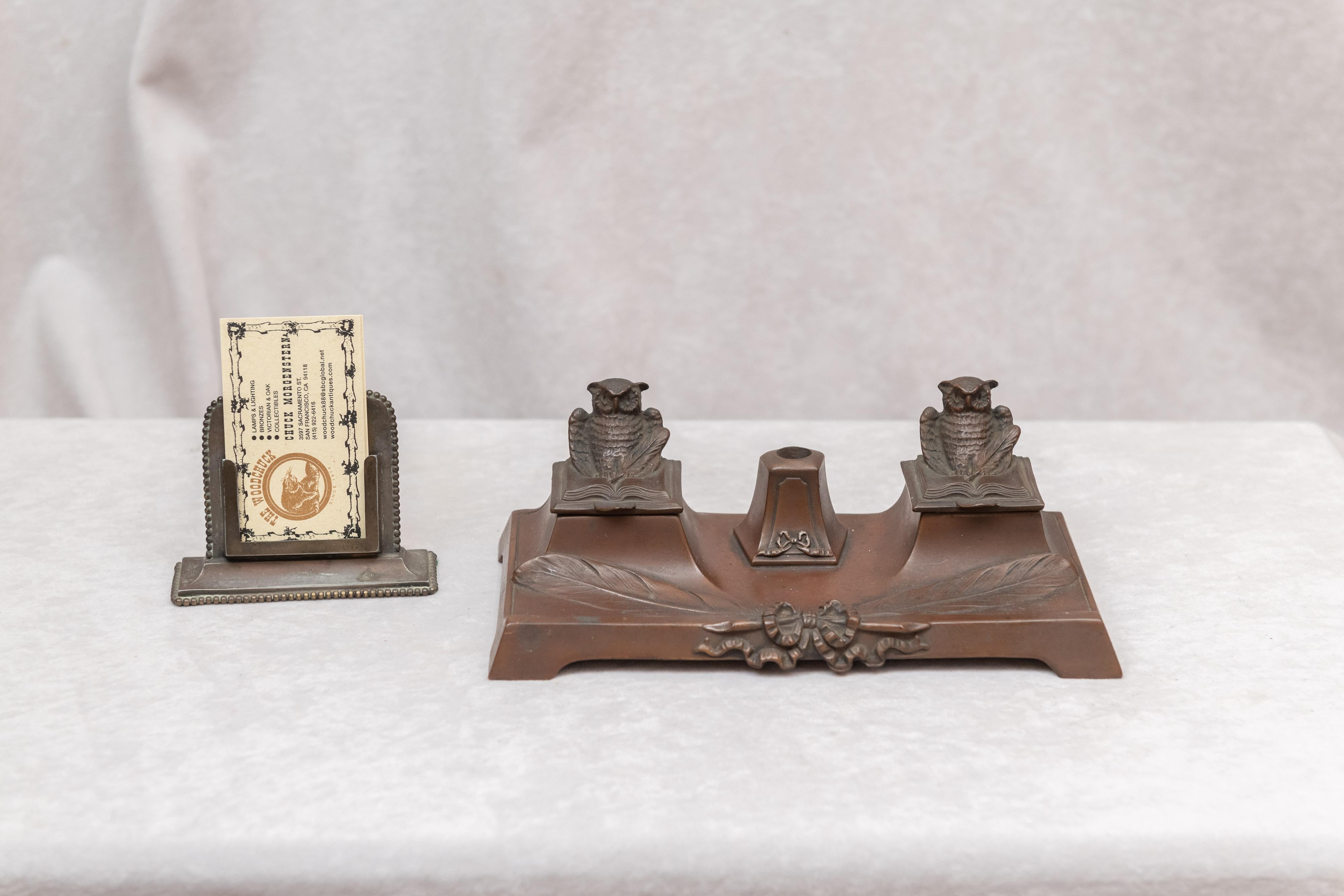 This very cute little inkwell is American and circa 1920. We believe it was made by Jennings Bros. The warm brown patina certainly points to them. The hole in the middle of the owls would be for your pen or pencil. It has been on our own desk for