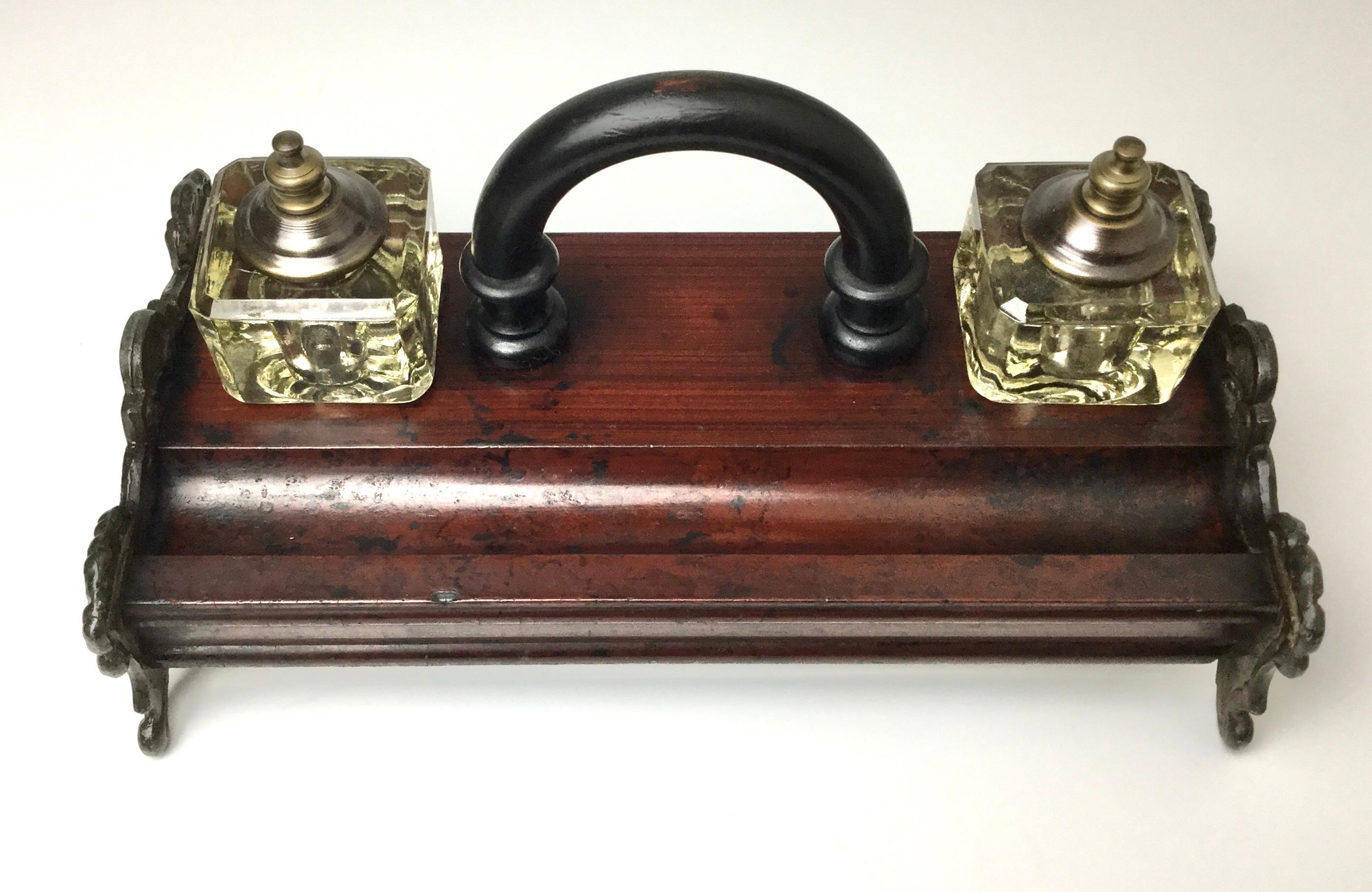 Late 19th century double fitted covered inkwells on what I believe to be cherrywood with cast iron footed sides and black ebony handle. 11' by 6' by 5' tall. Some age appropriate ware and some ink spots. Minor very small chip on corner.