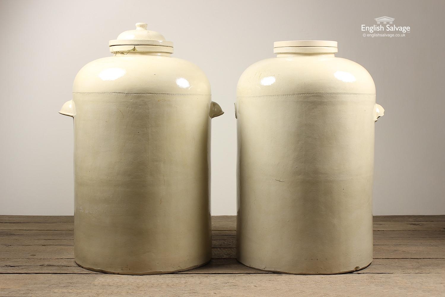 Two magnificent, vast, antique Doulton stoneware chemical storage jars with carry handles and bottom outlet. One jar has a lid (approx 110cm high) whilst the other has a bung like fitting (approx 104cm high). Both have the initials AJ embossed on