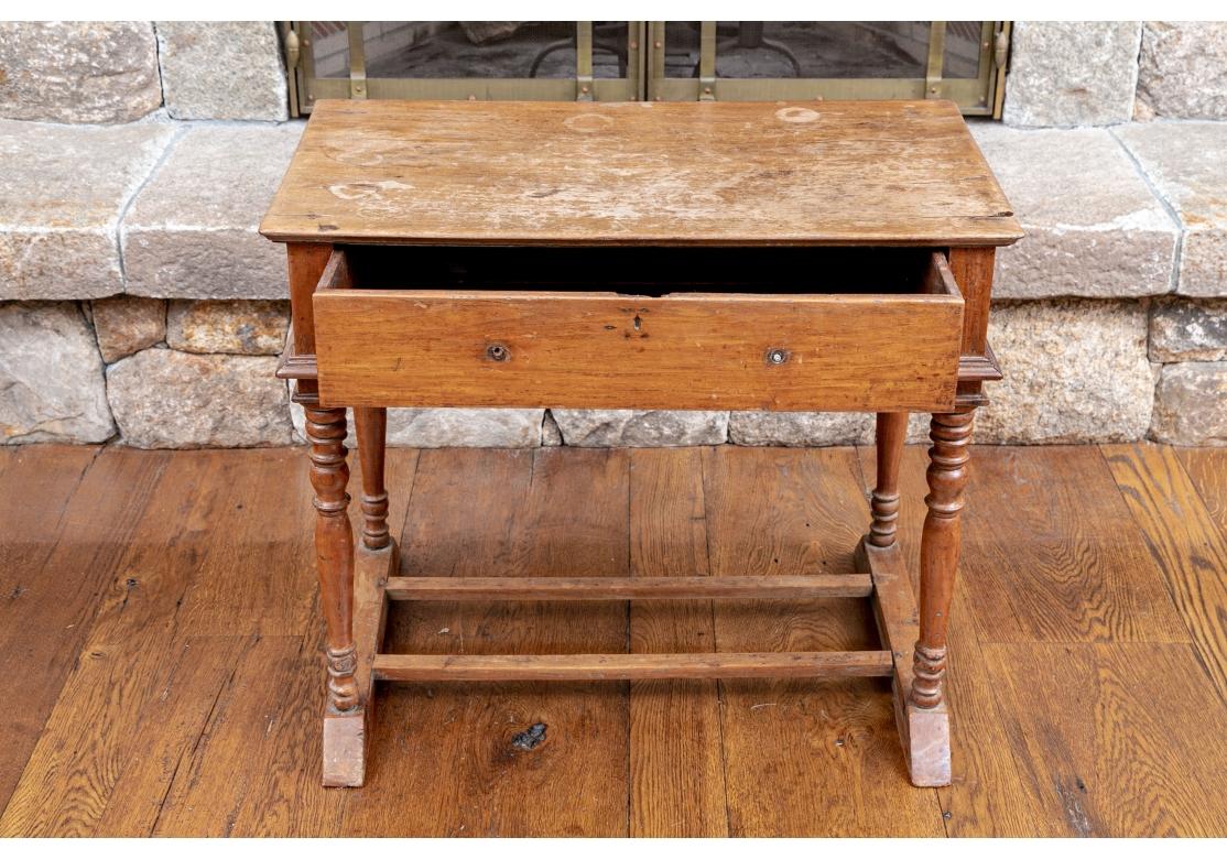 A small stand with a single apron drawer mounted on the carved base. The recessed frieze raised on turned legs mounted on a shaped trestle base with two square stretchers. 

L. 33
