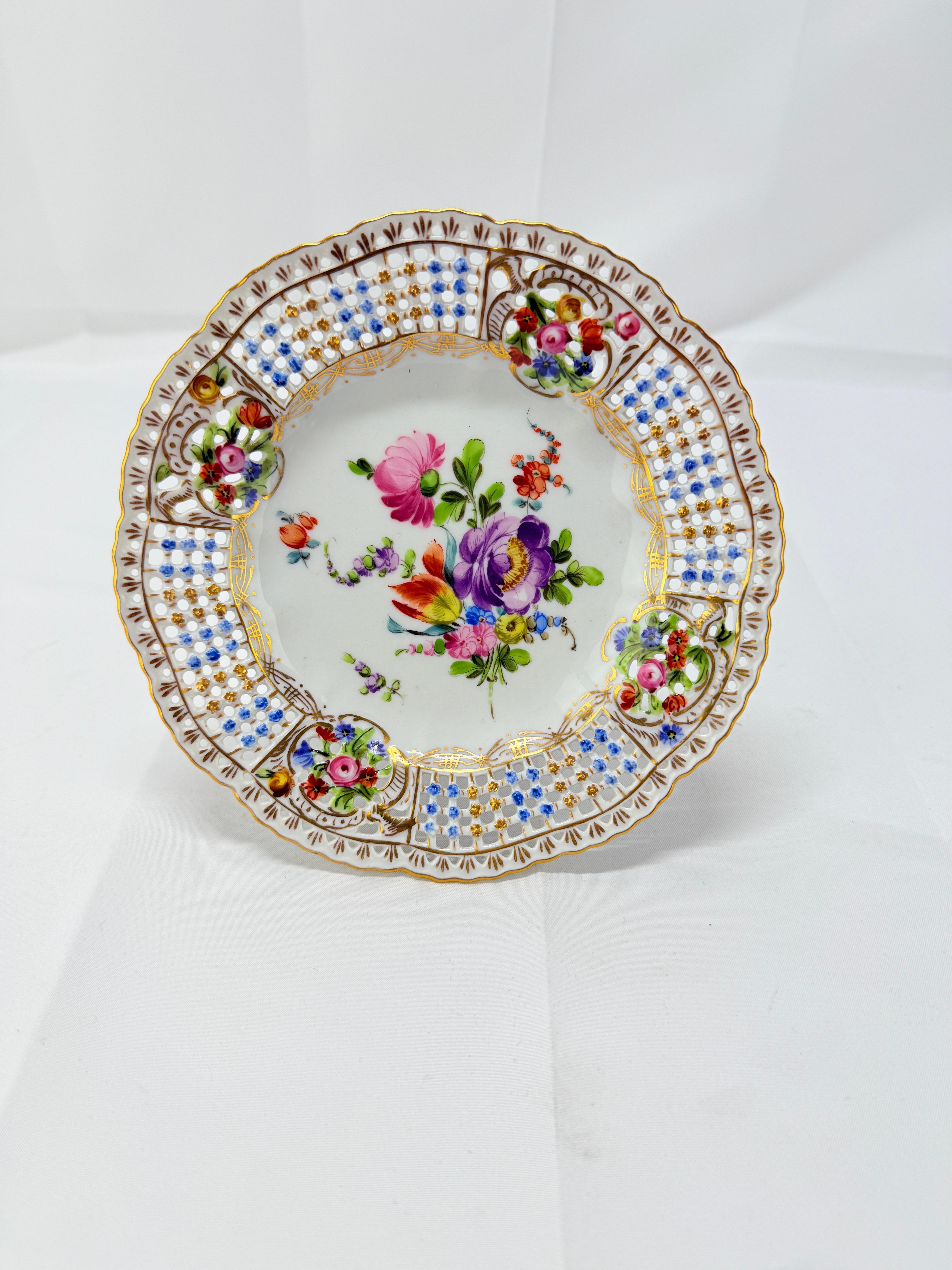 Esta compota de porcelana de Dresde con incrustaciones florales y perforaciones de principios del siglo XX conserva la elegancia atemporal y la sofisticada artesanía asociadas a la legendaria tradición de la porcelana de Dresde, mezclando tanto la