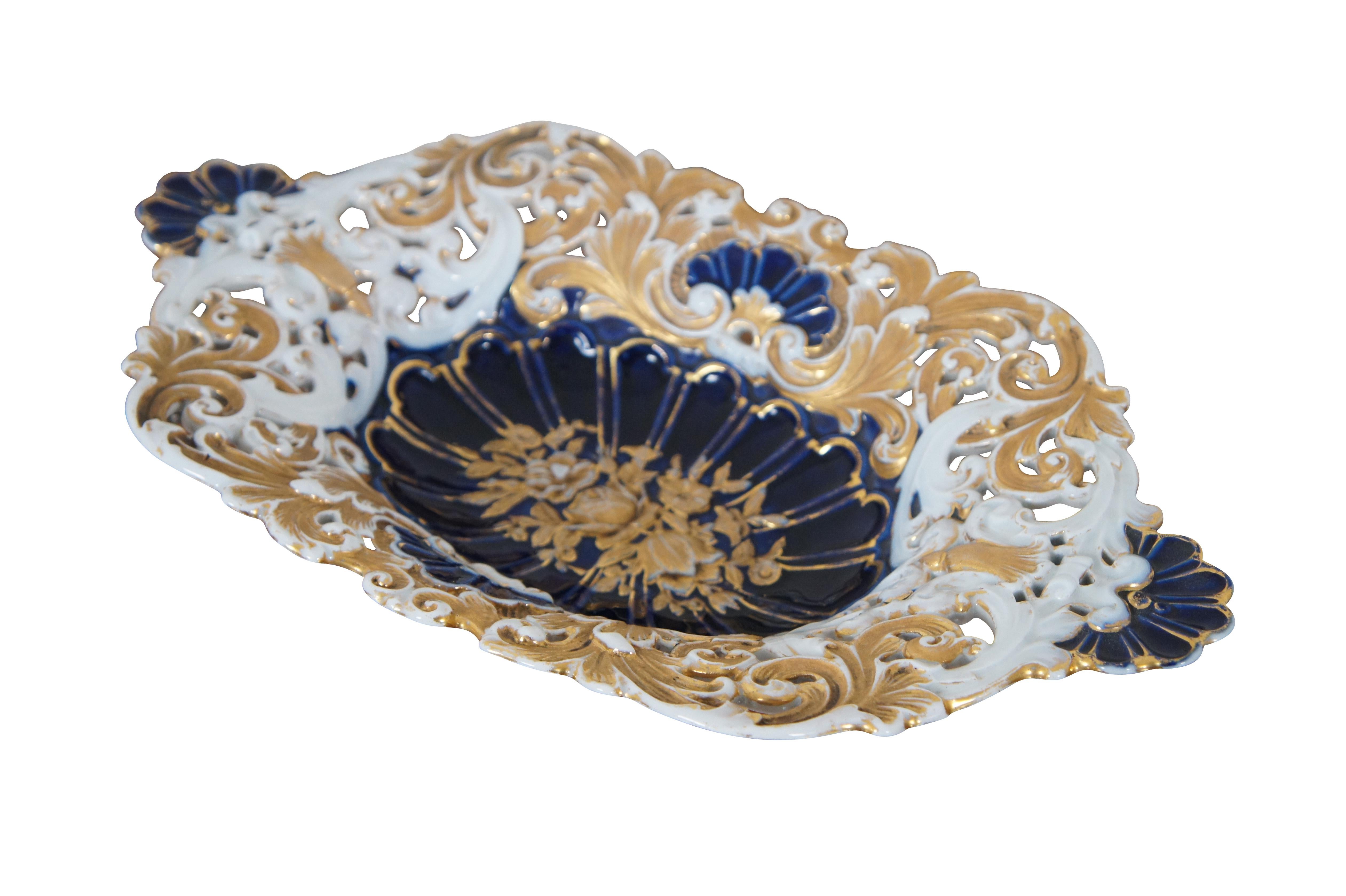 Antique German Meissen porcelain footed cabinet plate / centerpiece bowl / serving platter / compote featuring scalloped oval form with low relief reticulated design of gold gilt roses and acanthus leaves with cobalt blue shell handles and footed