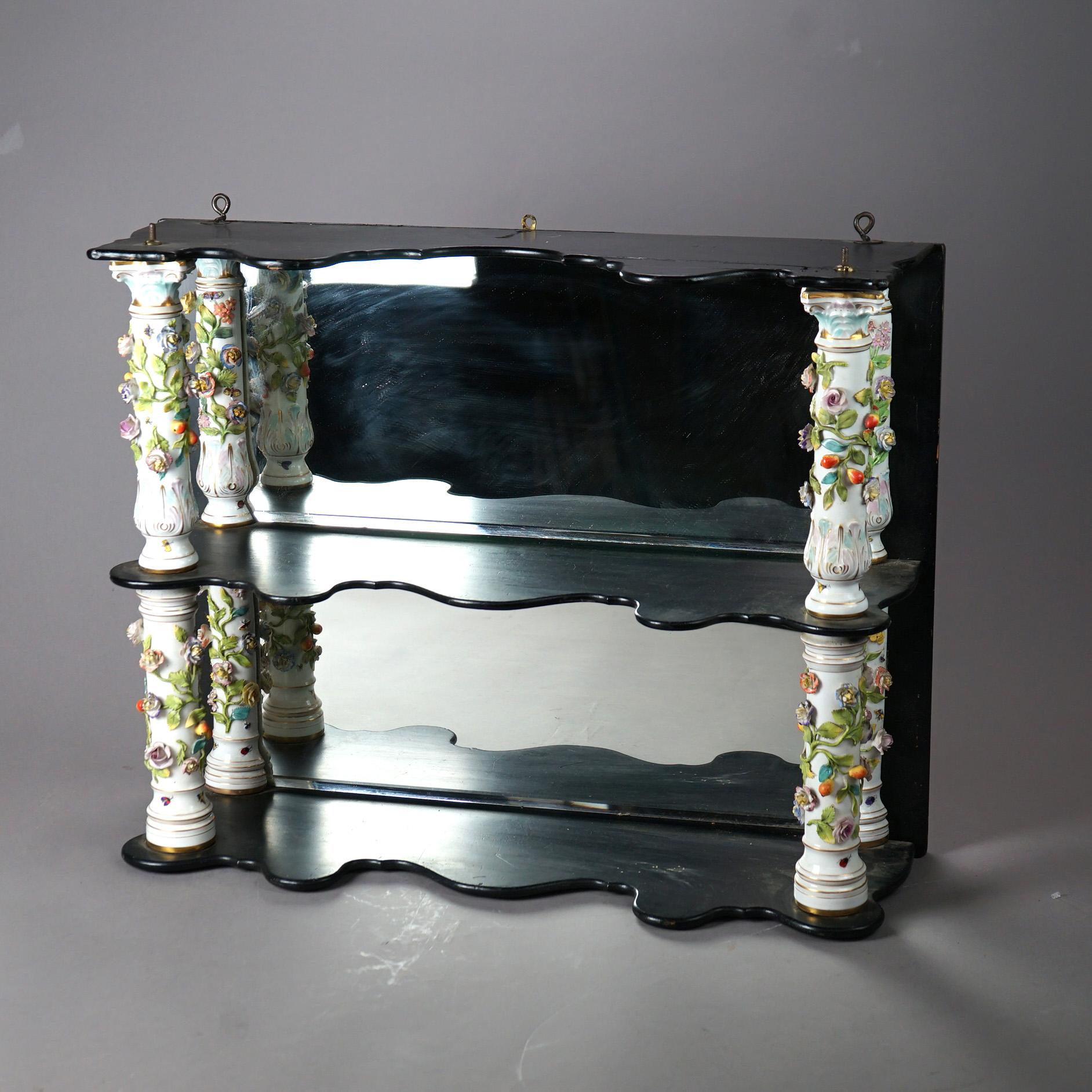 An antique wall shelf offers shaped ebonized wood shelves with Dresden porcelain supports having hand painted applied flowers and mirrored back, c1890

Measures - 21.5