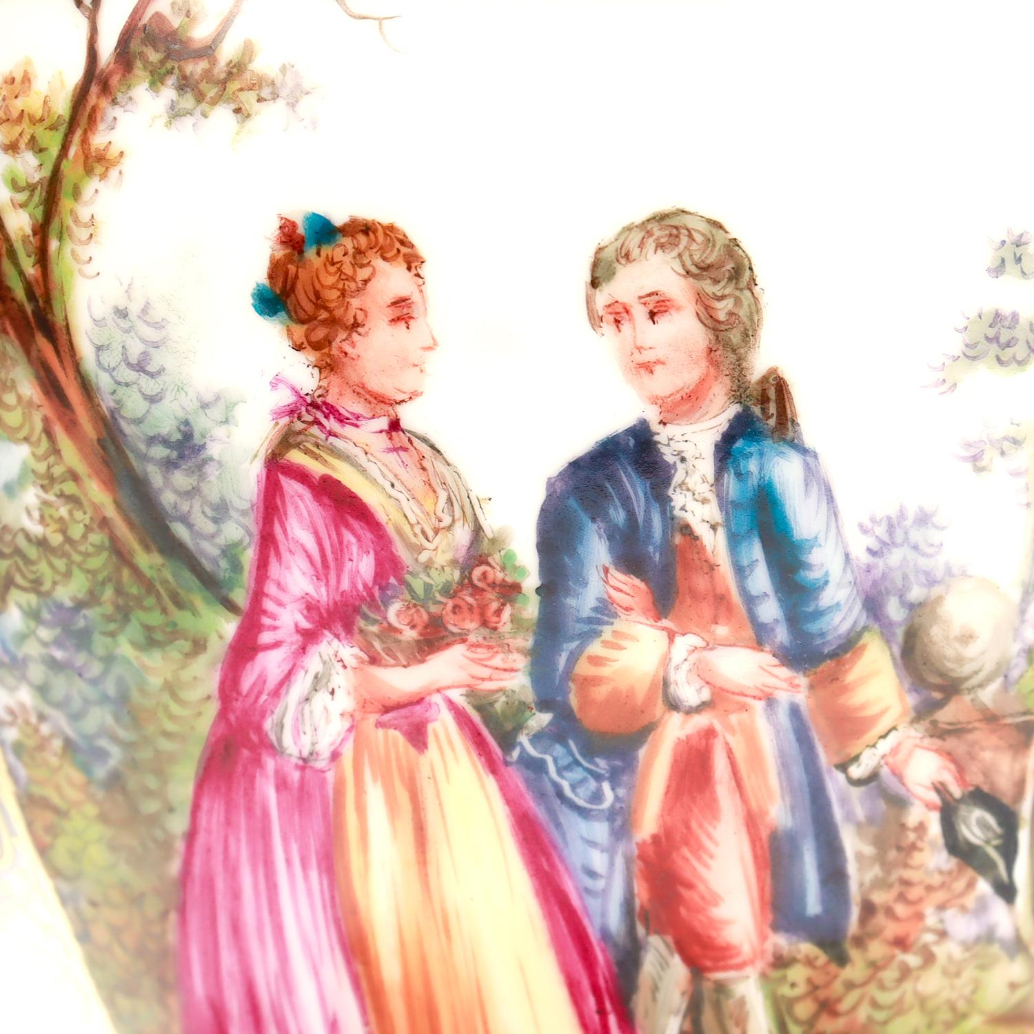 Una bella urna o vaso antico di Dresda.

Con un'alternanza di pannelli rosa con fiori sparsi e pannelli con raffigurazioni di amanti galanti in un giardino.

Evidenziato in tutto con decorazioni ornamentali dorate. 

Semplicemente una meravigliosa