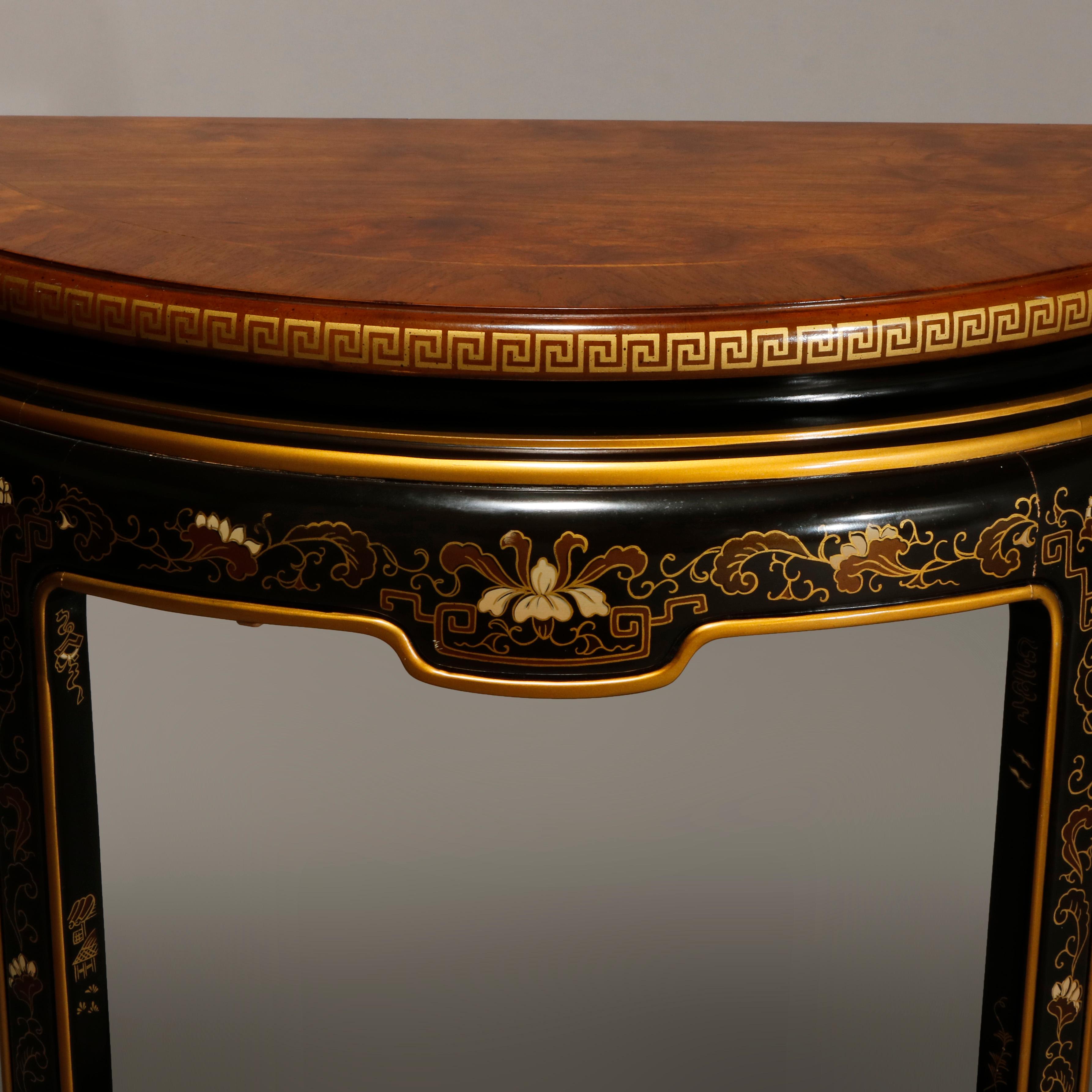 An antique console by Drexel Heritage offers demilune form with flame mahogany cross banded top having gilt Greek Key bornering and surmounting ebonized base having foliate and scroll Chinoiserie decoration with gilt highlights throughout, makers