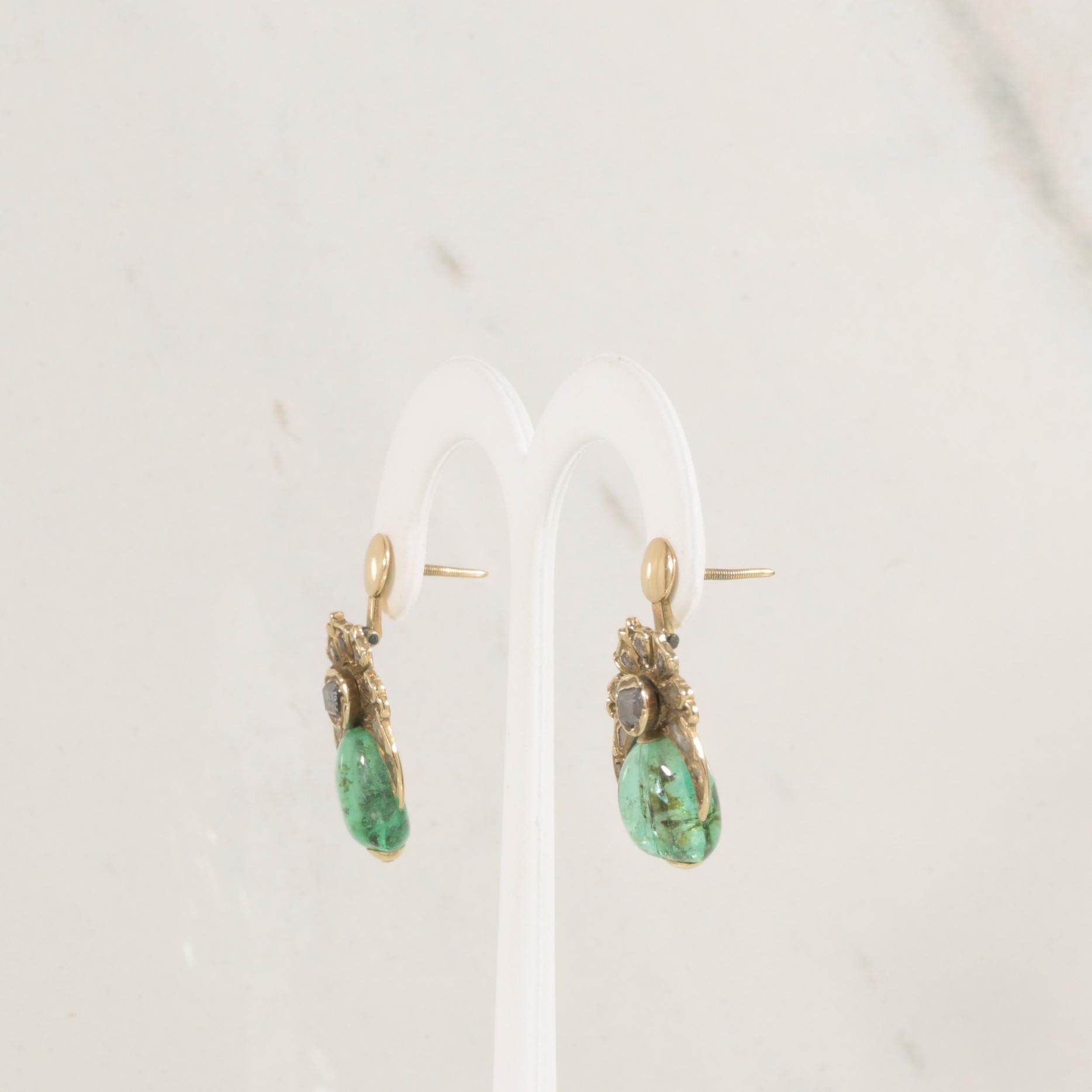 Diese antiken Ohrringe sind mit exquisiten, gebohrten Smaragd-Cabochons versehen und bieten einen leuchtenden grünen Farbtupfer mit zeitlosem Reiz. Jeder Smaragd wird durch Diamanten im Rosenschliff ergänzt, die in komplizierte 14-karätige