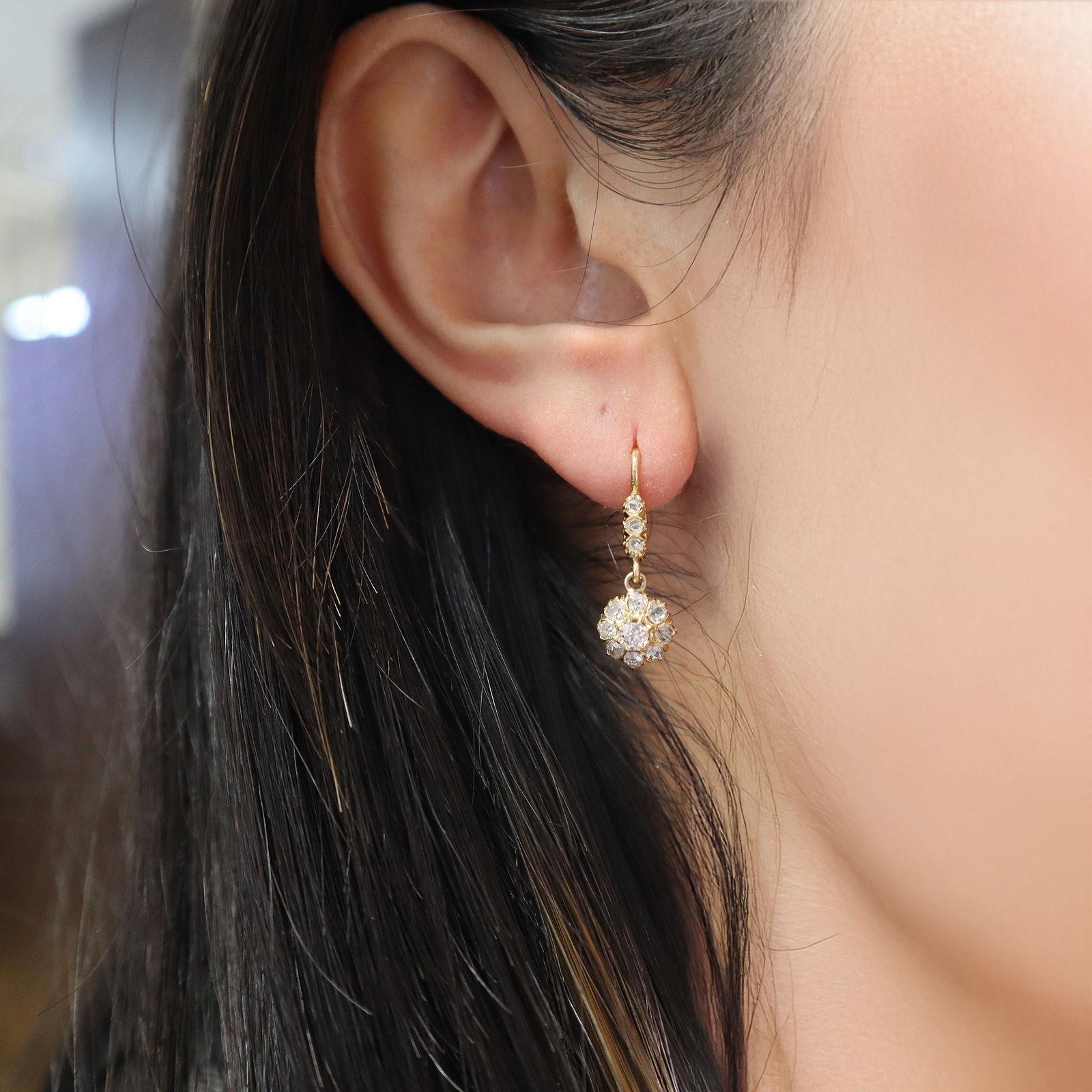 This elegant pair of antique Rosetta drop earrings is crafted in 18kt yellow gold, featuring two center old mine natural diamonds together weighing approximately 0.28 carats (H color, VS2 clarity). The centers are beautifully surrounded by 16