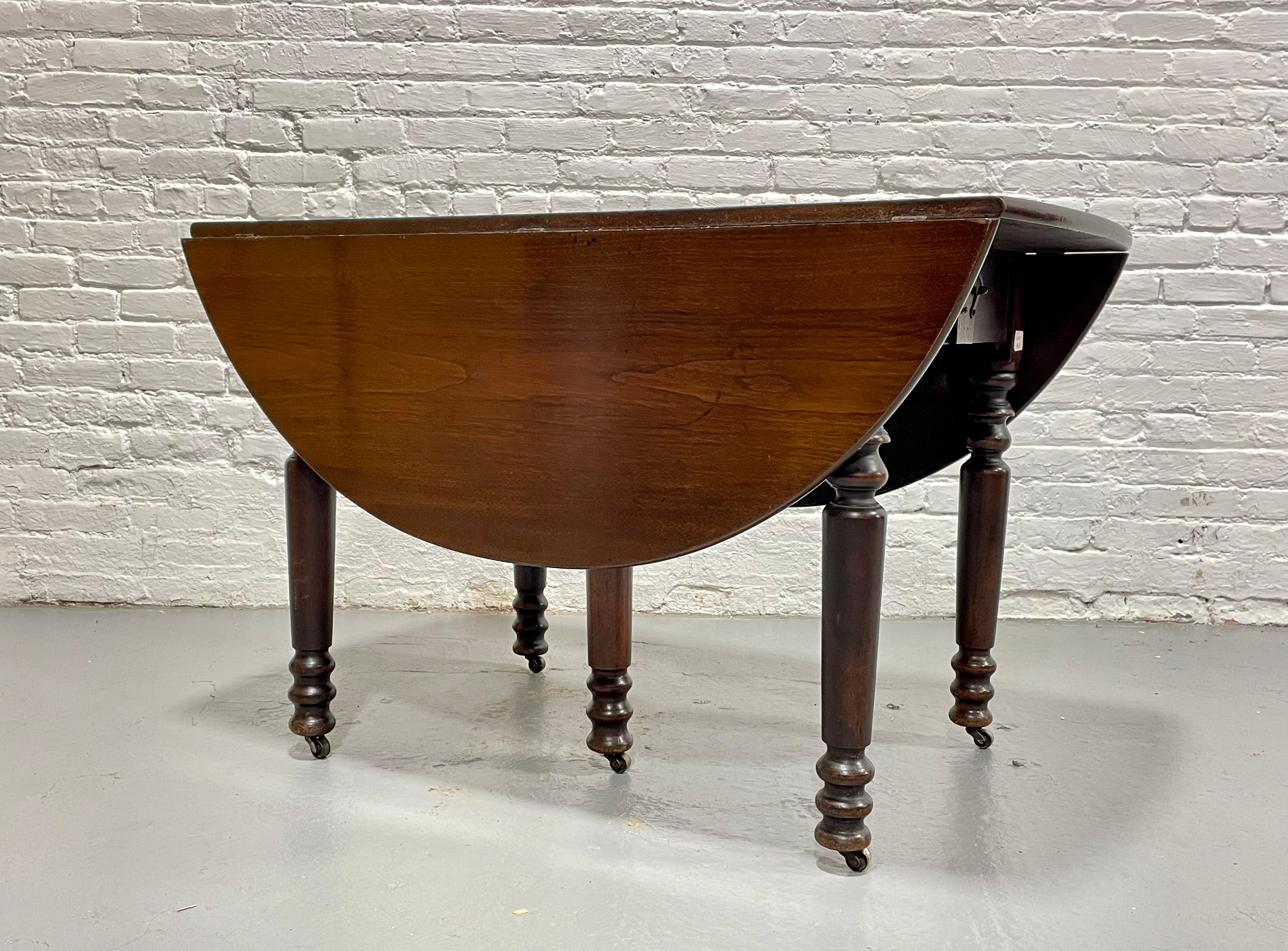 The most perfect apartment size Antique Drop Leaf Oval Extendable Dining Table, c. 1910. This incredible piece transforms from a small two person dining table to seat as many as 8-10 guests. The table features two drop leaves that flip open to