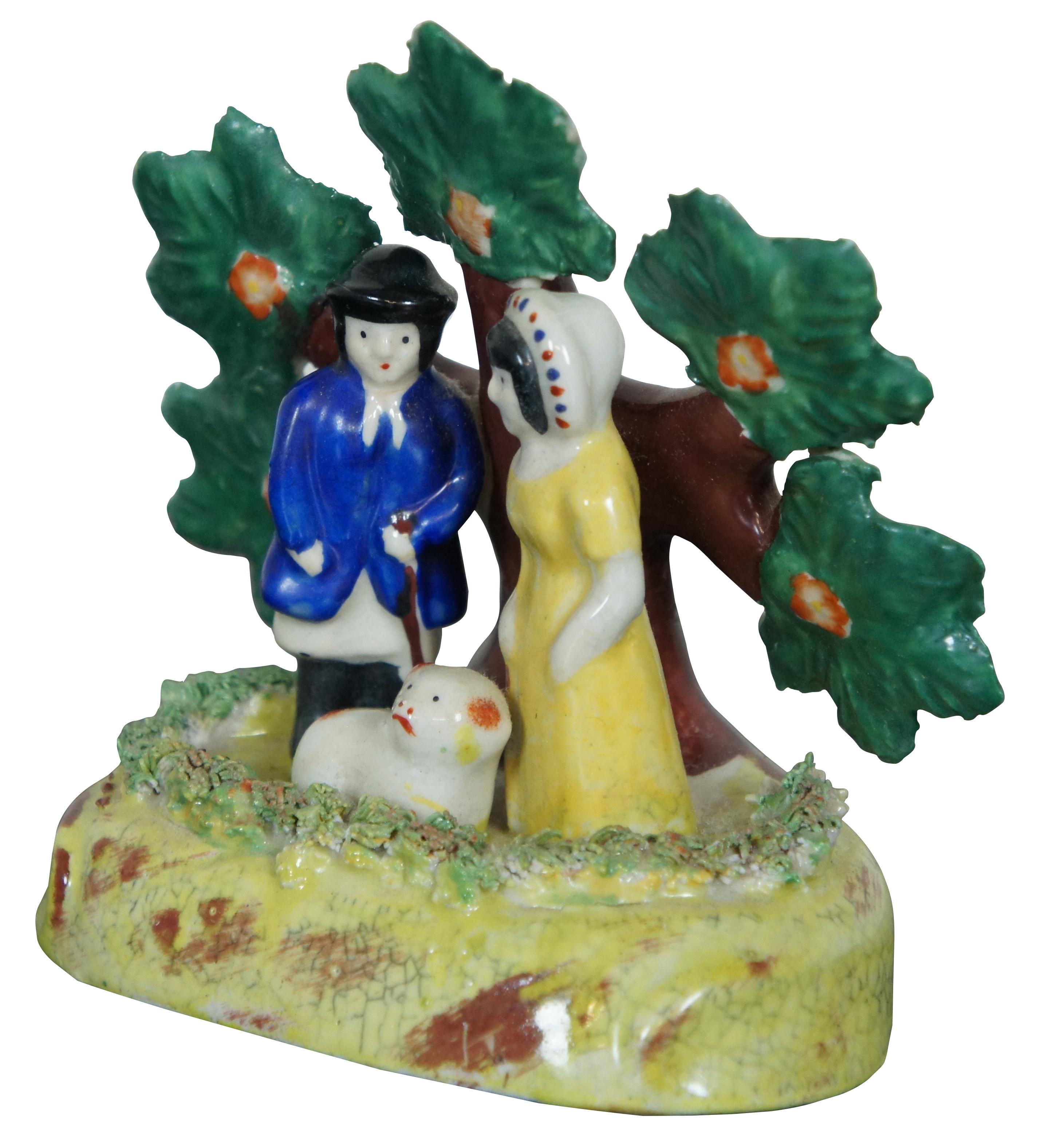 Antique early English Staffordshire porcelain pearlware bocage group, showing male and female shepherds with a red and white lamb, standing in front of a flowering tree.  Attributed to the James Dudson factory at Stoke on Trent, circa 1830-1860.