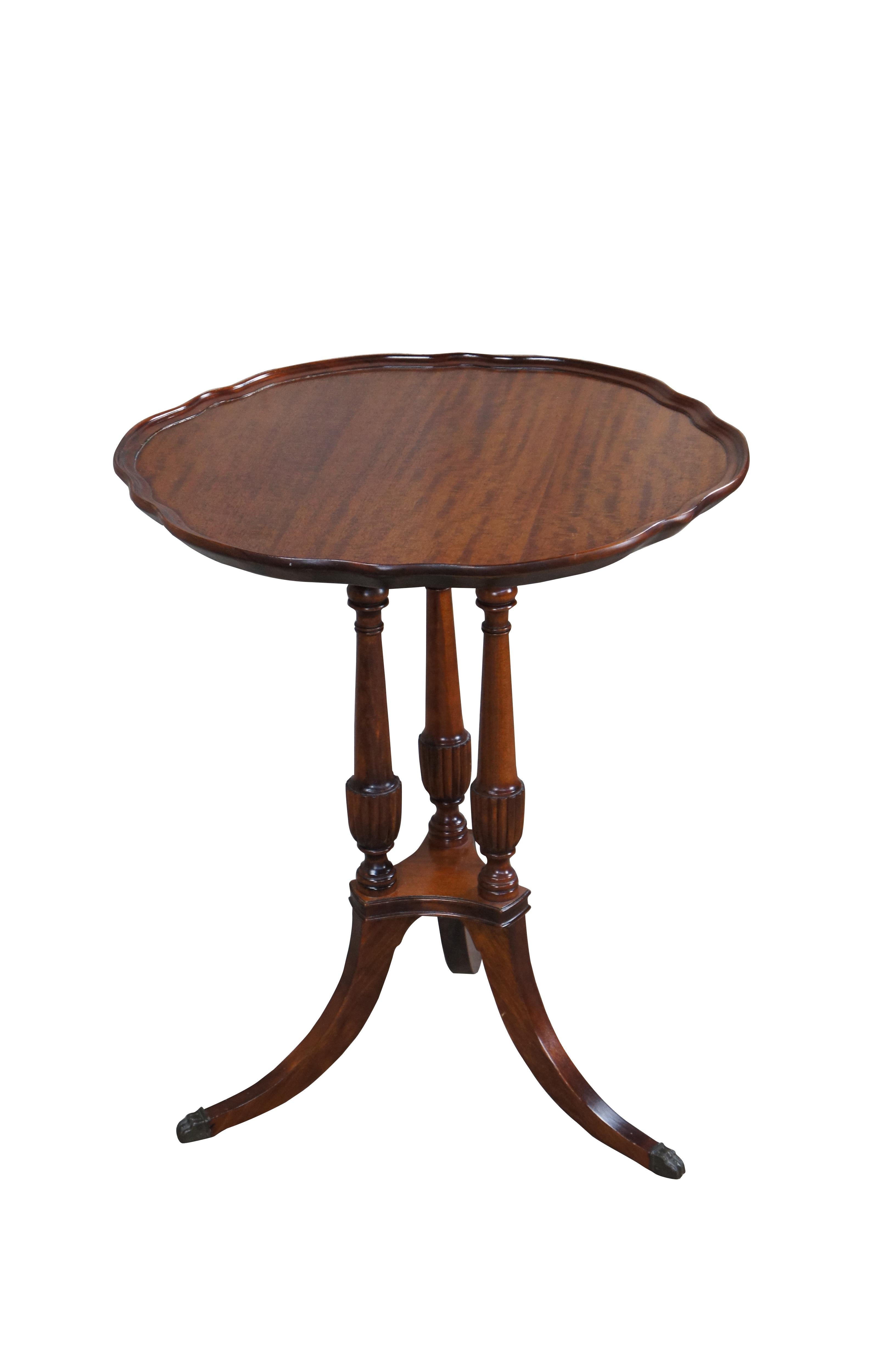 Antique Duncan Phyfe pie crust tea table. Made of mahogany featuring scalloped gallery top supported by tri foot pedestal base with brass capped feet.

Dimensions:
23