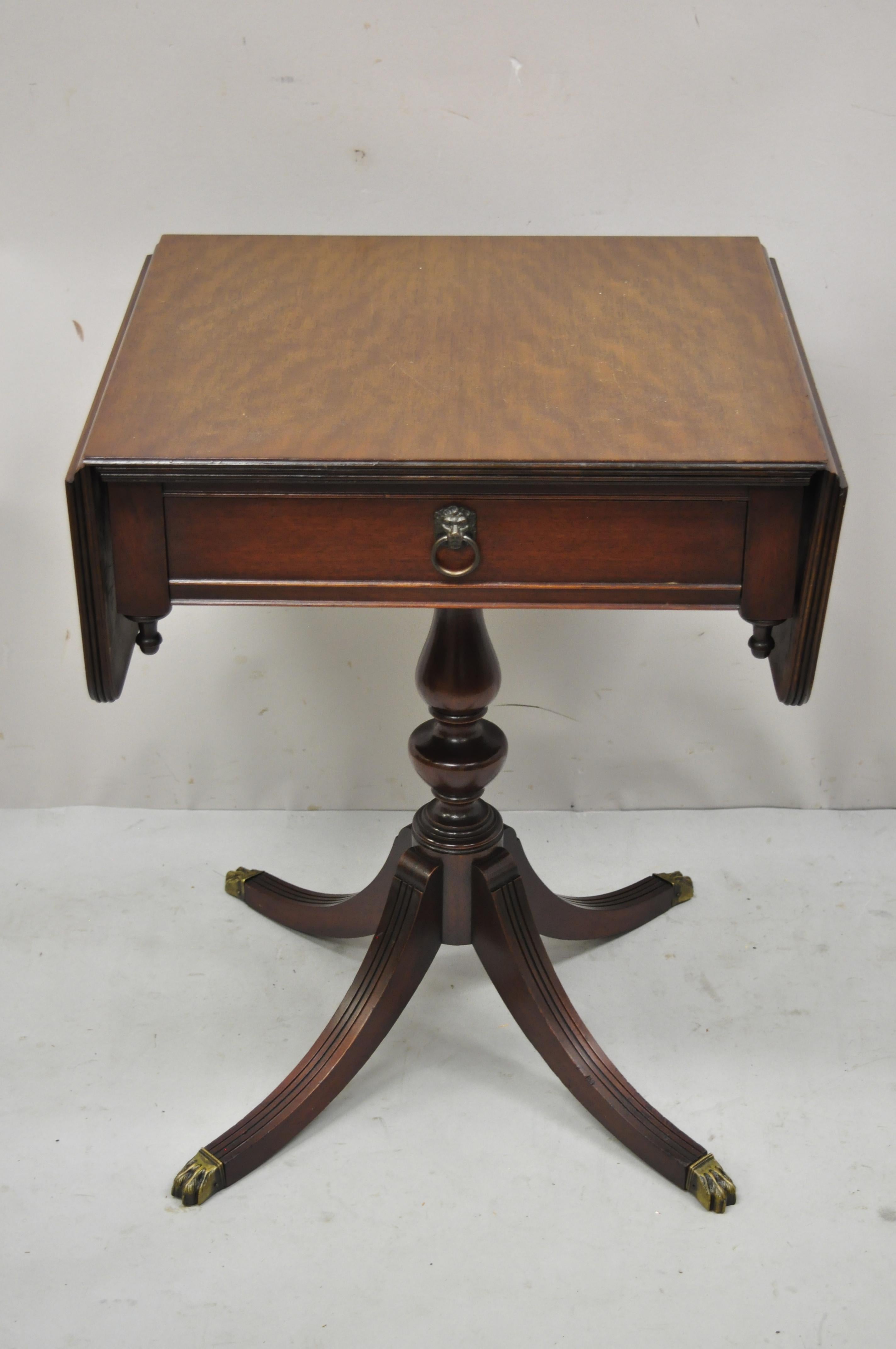 Antique Duncan Phyfe pedestal base mahogany dropleaf Pembroke lamp side table. Item features brass claw feet, pedestal base, drop sides, brass lion head drawer pulls, beautiful wood grain, 1 dovetailed drawer, very nice antique item, great style and