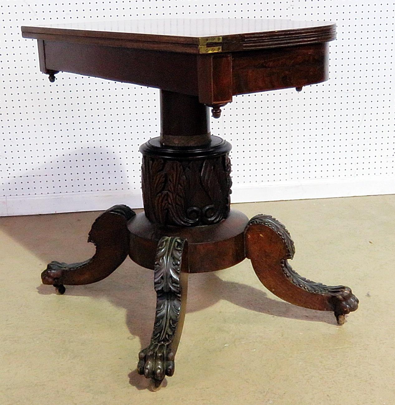 Antique Duncan Phyfe style flip top card table with claw feet on casters.