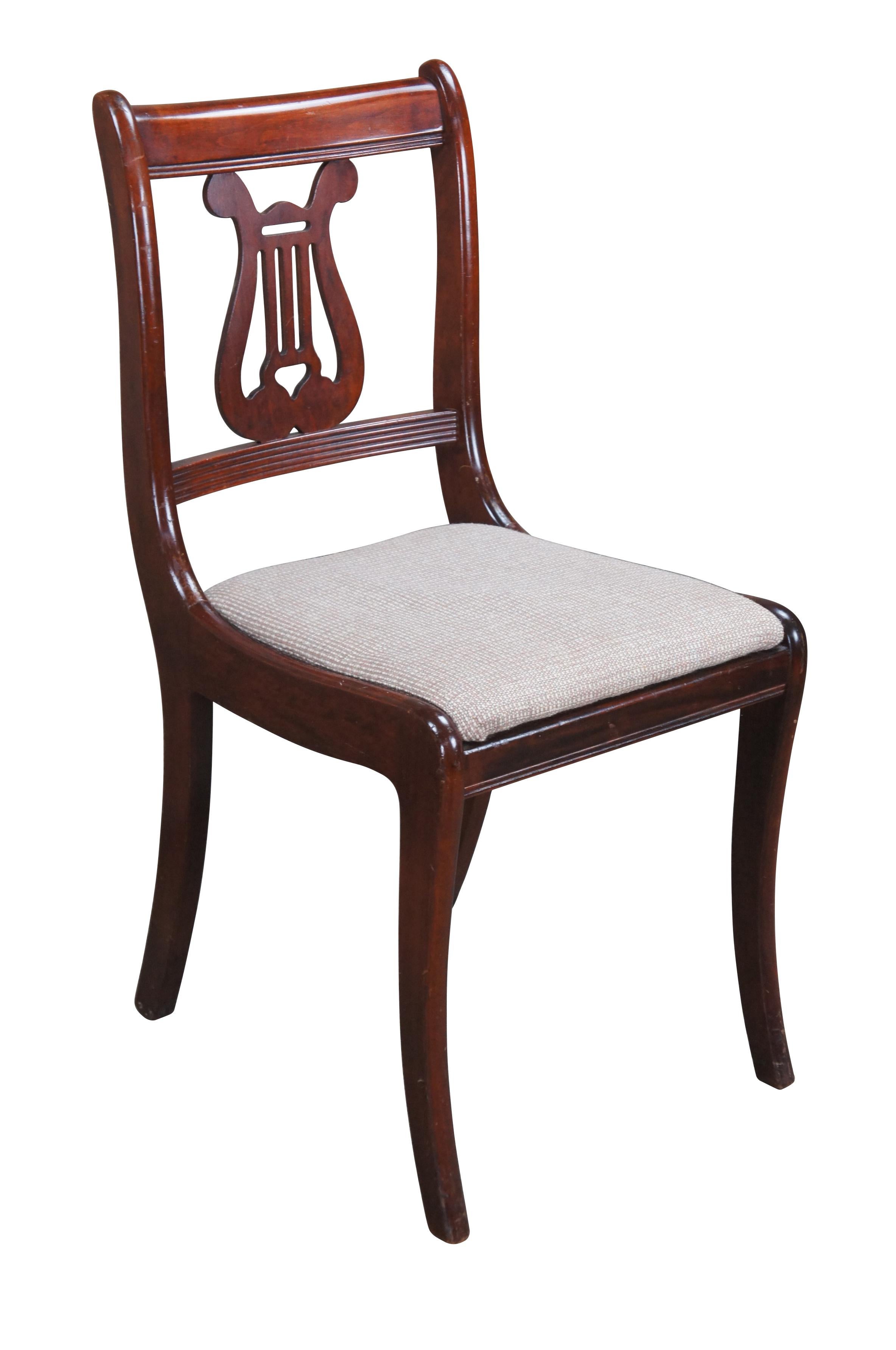 Sedia da pranzo in stile Duncan Phyfe / Regency del 1940.  Realizzato in mogano con il retro di un'arpa/lira.  Presenta una seduta imbottita e gambe a sciabola.

Dimensioni:
17
