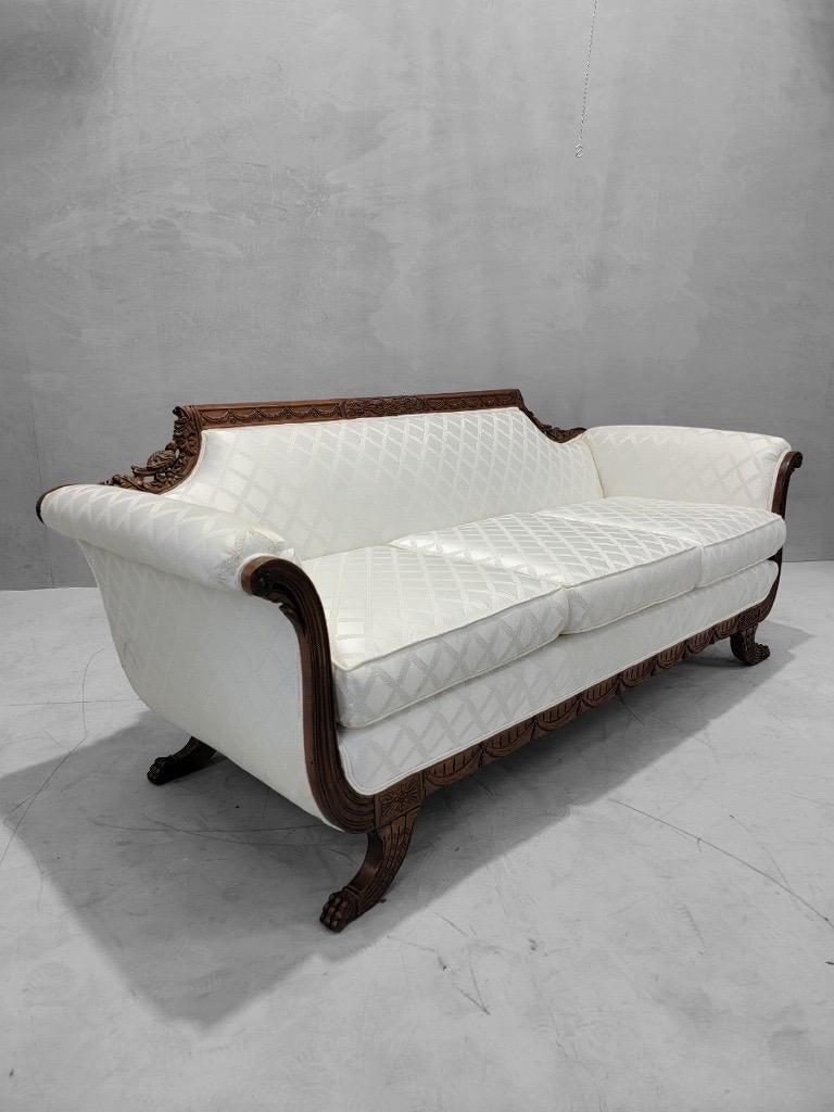 Antico divano da salotto in mogano finemente intagliato in stile Duncan Phyfe e rivestito con un'elegante tappezzeria in misto seta a motivi bianchi

Questo antico divano da salotto in stile Duncan Phyfe presenta intricati intagli ed è realizzato in
