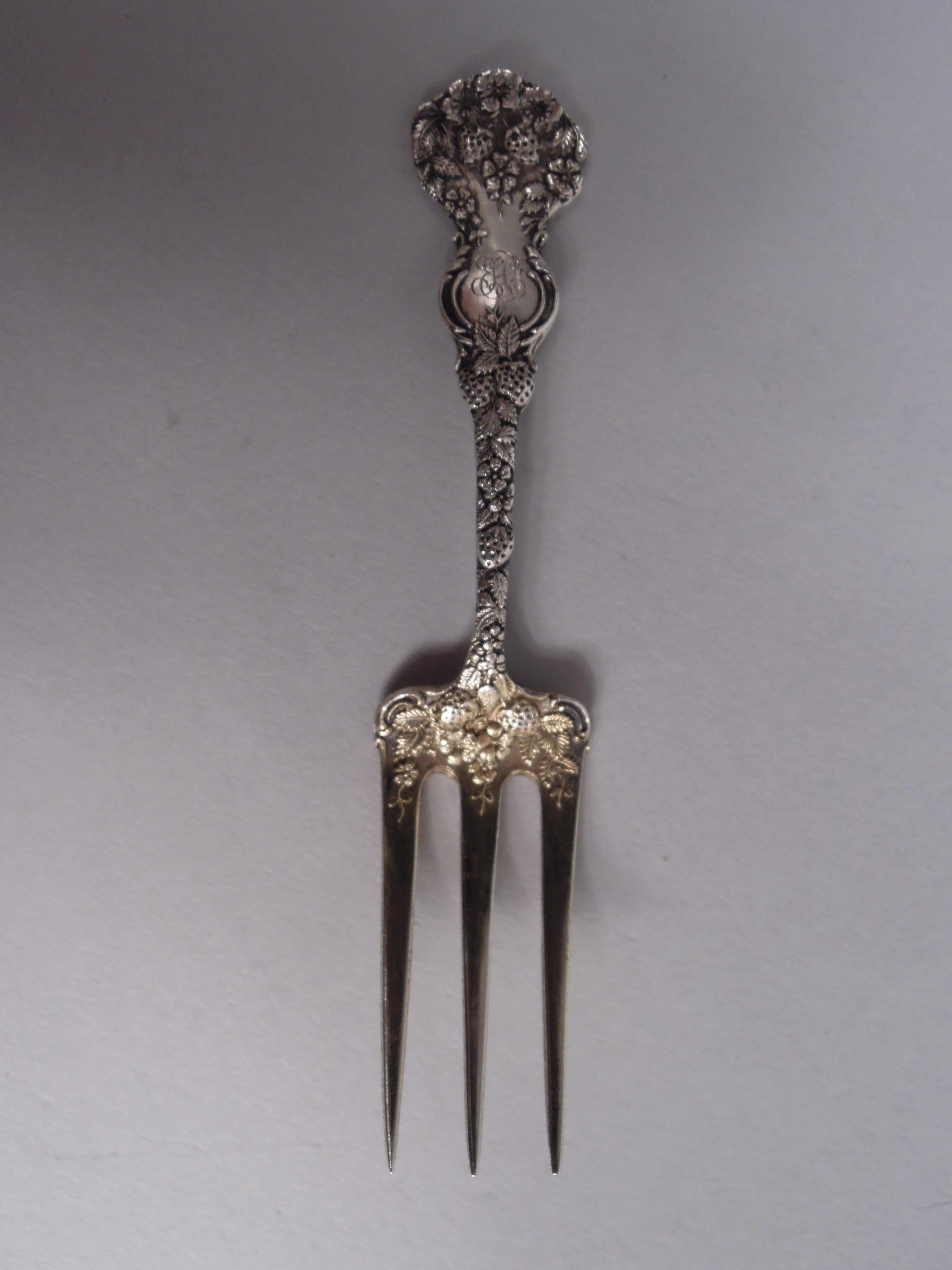 Set of 6 Victorian sterling silver strawberry forks. Made by William B. Durgin in Concord, ca 1900. Each: Short and shaped stem and rectilinear shank with three tines. Dense fruiting strawberry branch. Engraved interlaced script monogram. Fully