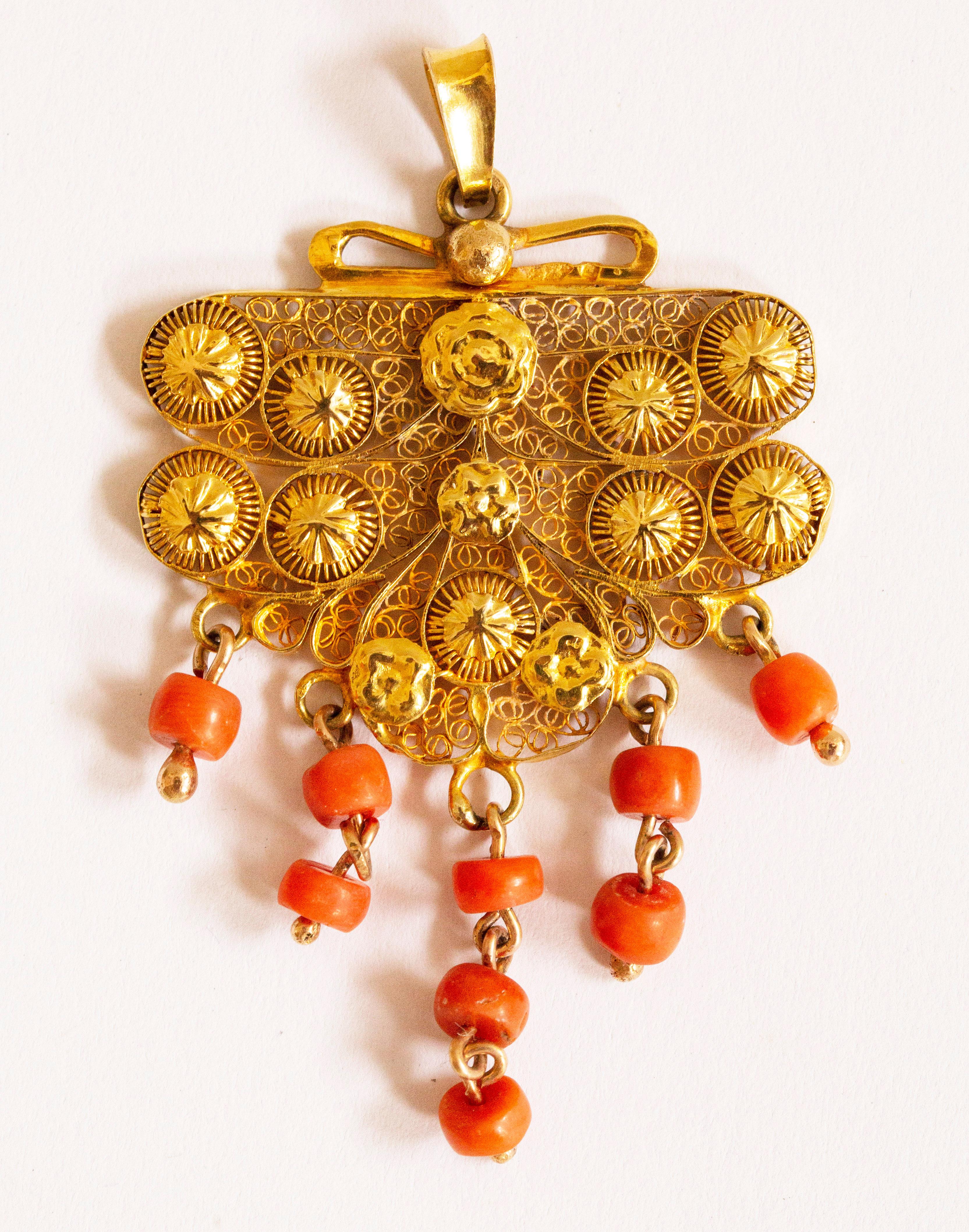 An antique Dutch 14 karat and red coral filigree pendant. The pendant is made from a lock of the traditional  Dutch costume worn around 1900 in a province called Zeeland. The pendant is made with filigree technique. Filigree is a very refined