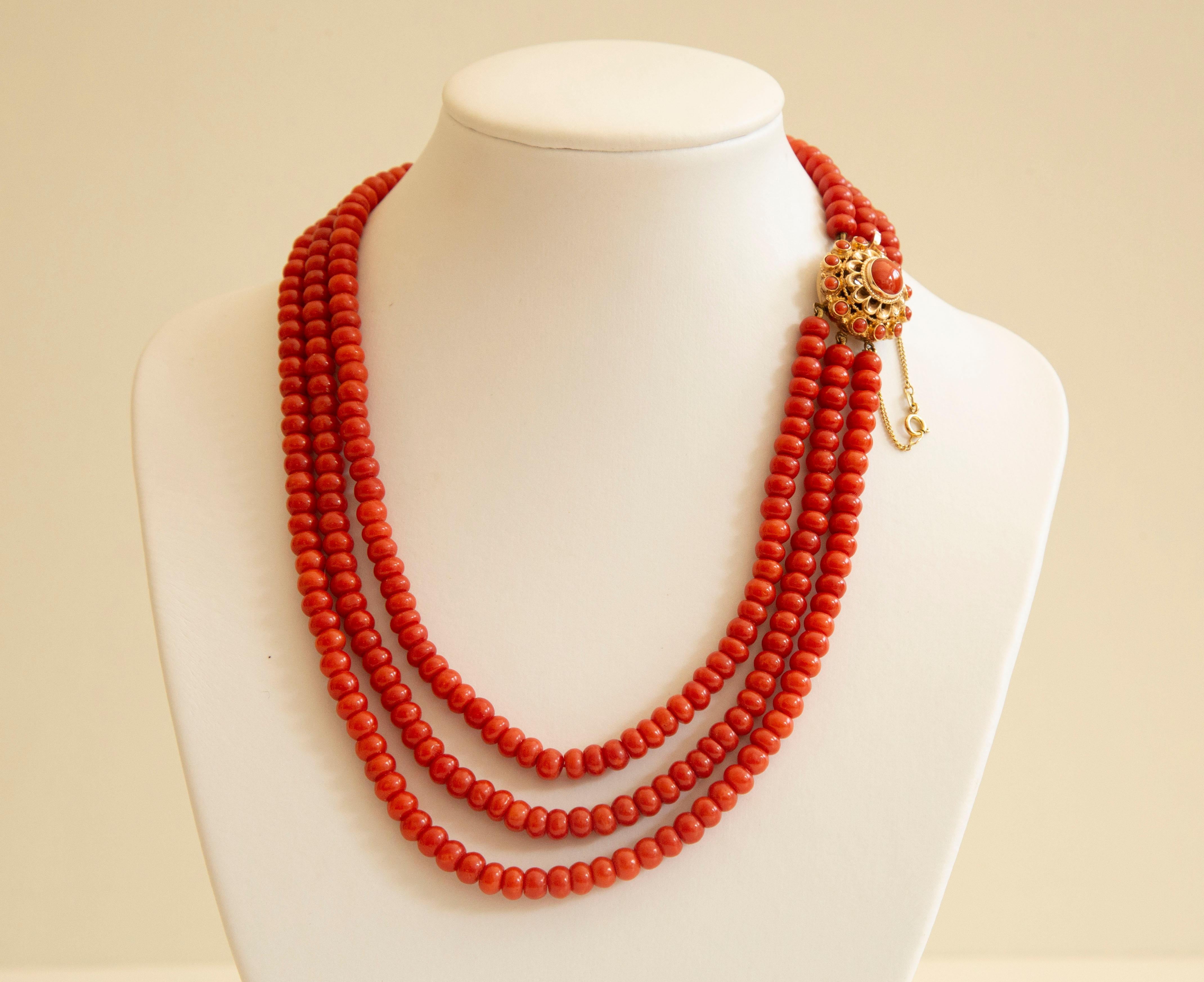 An antique 3-row natural red coral  (Corallium Rubrum*) choker necklace with round filigree 14 karat yellow clasp, from ca. 1945, the Netherlands. The beads have a round and regular shape. The size of the beads is CA. 5 mm in diameter. The clasp