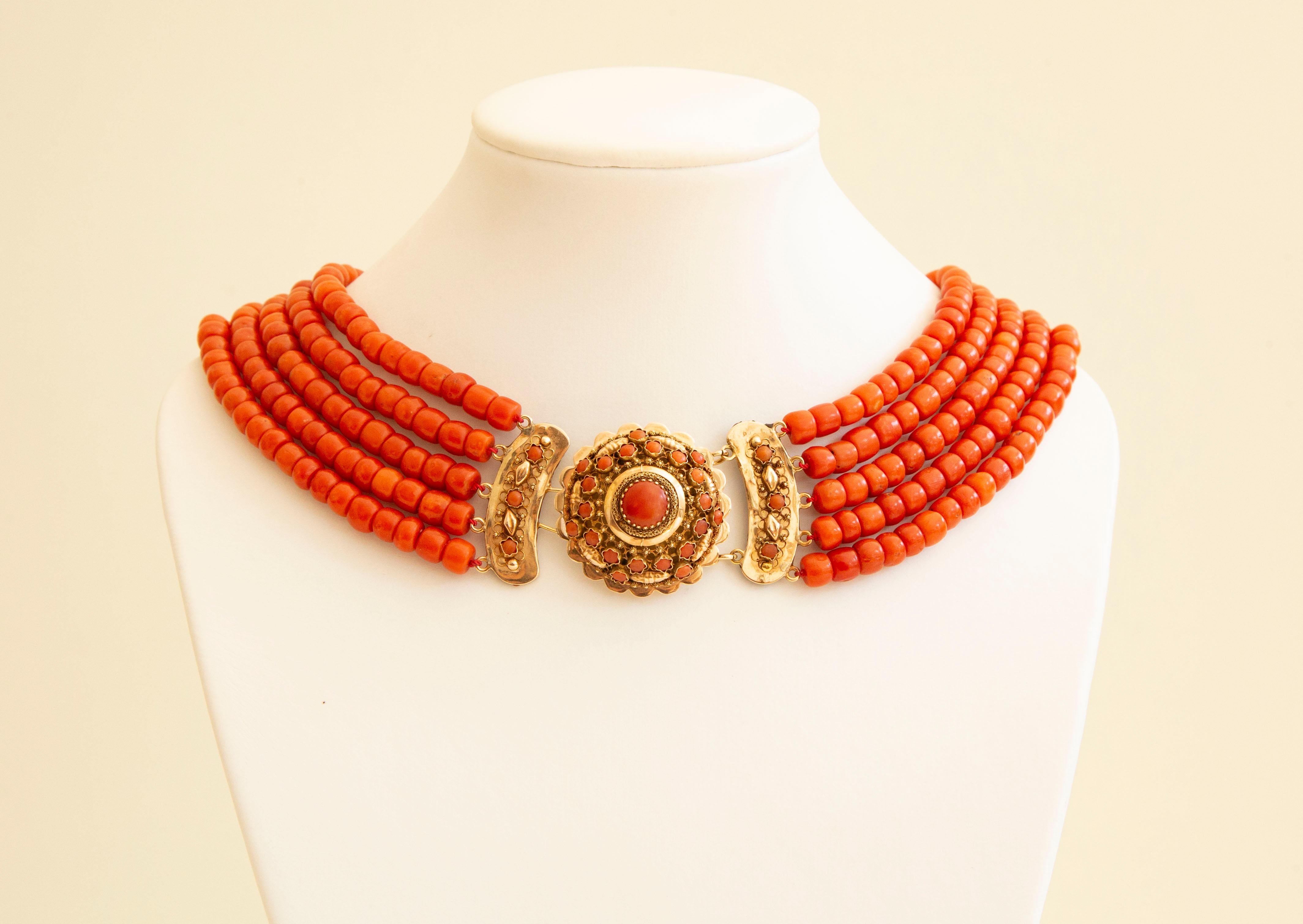 An antique 5-row natural red coral necklace with filigree 14 karat yellow closure decorated with red coral beads. The closure consists of half-dome element featuring a golden filigree wire and cannetille decoration. In the centre there is one red