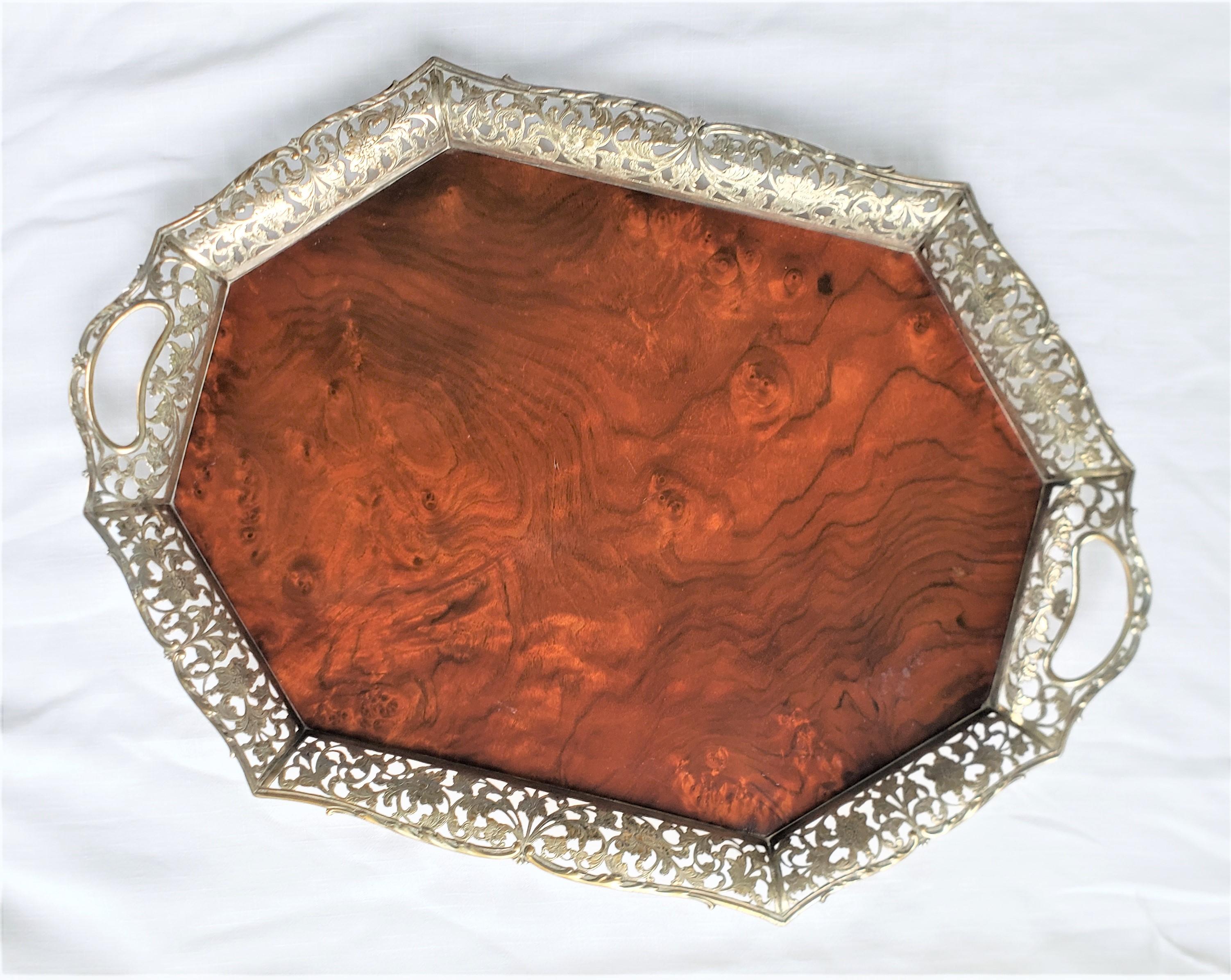 This antique serving tray has no maker's mark, but originated from the Netherlands and dates to approximately 1920 and done in an Art Nouveau style. The base of the tray is done in a lacquered burled walnut which accents the pierced solid silver