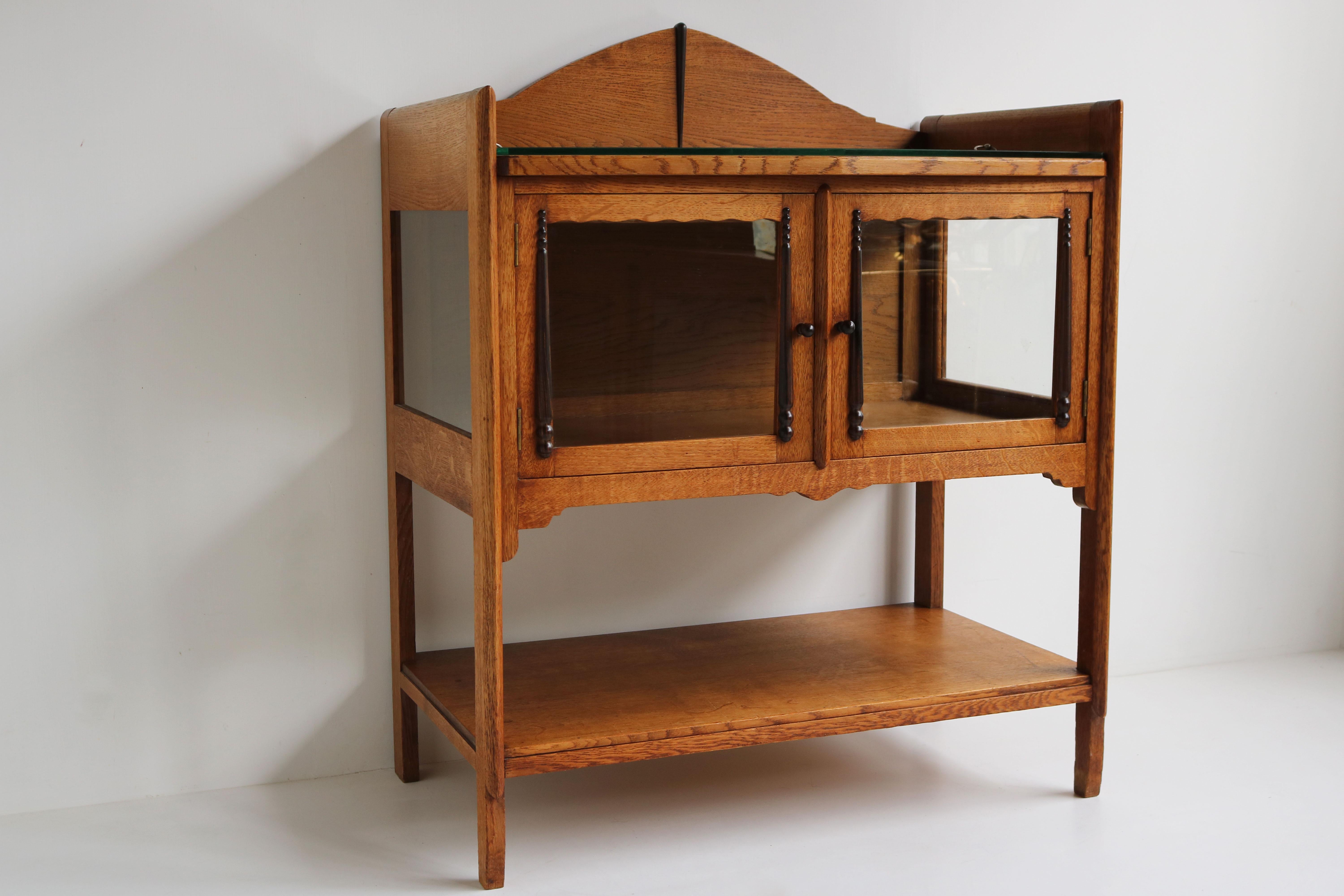 Gorgeous Dutch antique Amsterdam School style tea cabinet. Striking Dutch Art Deco design from the 1920s . 
The blonde oak looks amazing with the typical Amsterdam School Art Deco decorations in Macassar wood. 
The cabinet has glass on 3 sides & a