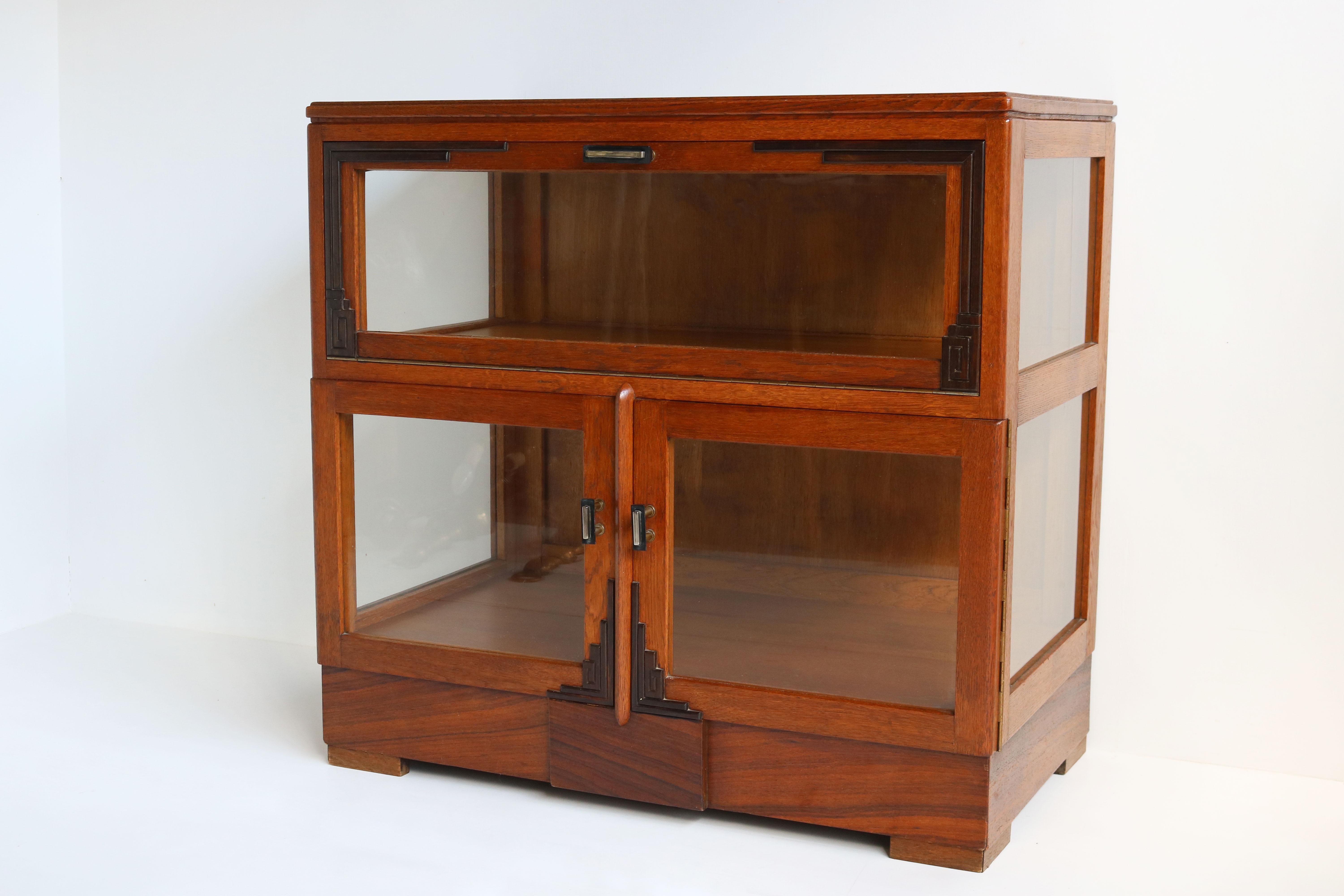Gorgeous Dutch antique Amsterdam School style tea cabinet. Striking Dutch Art Deco design from the 1920s . 
The blonde oak looks amazing with the typical Amsterdam School Art Deco decorations in Macassar wood. 
The cabinet has glass on 3 sides.