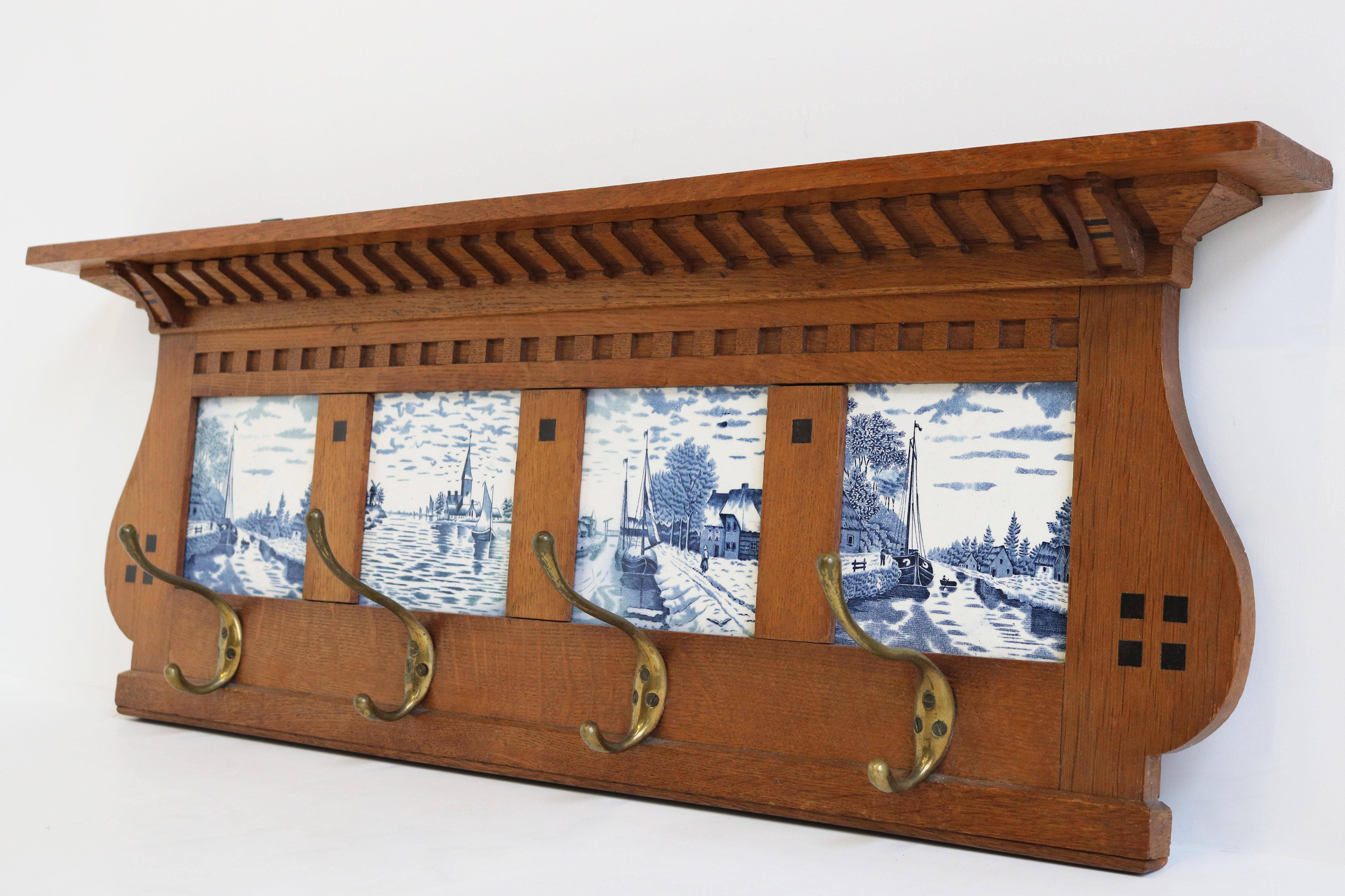 Charming & practical! This Dutch Delft blue Art Deco coat rack / hat rack from the 1930s. 
Marvelous coat rack made out of European oak with black Amsterdam school accents , brass hooks and 4 Dutch Delft Blue art tiles 
The original brass hooks