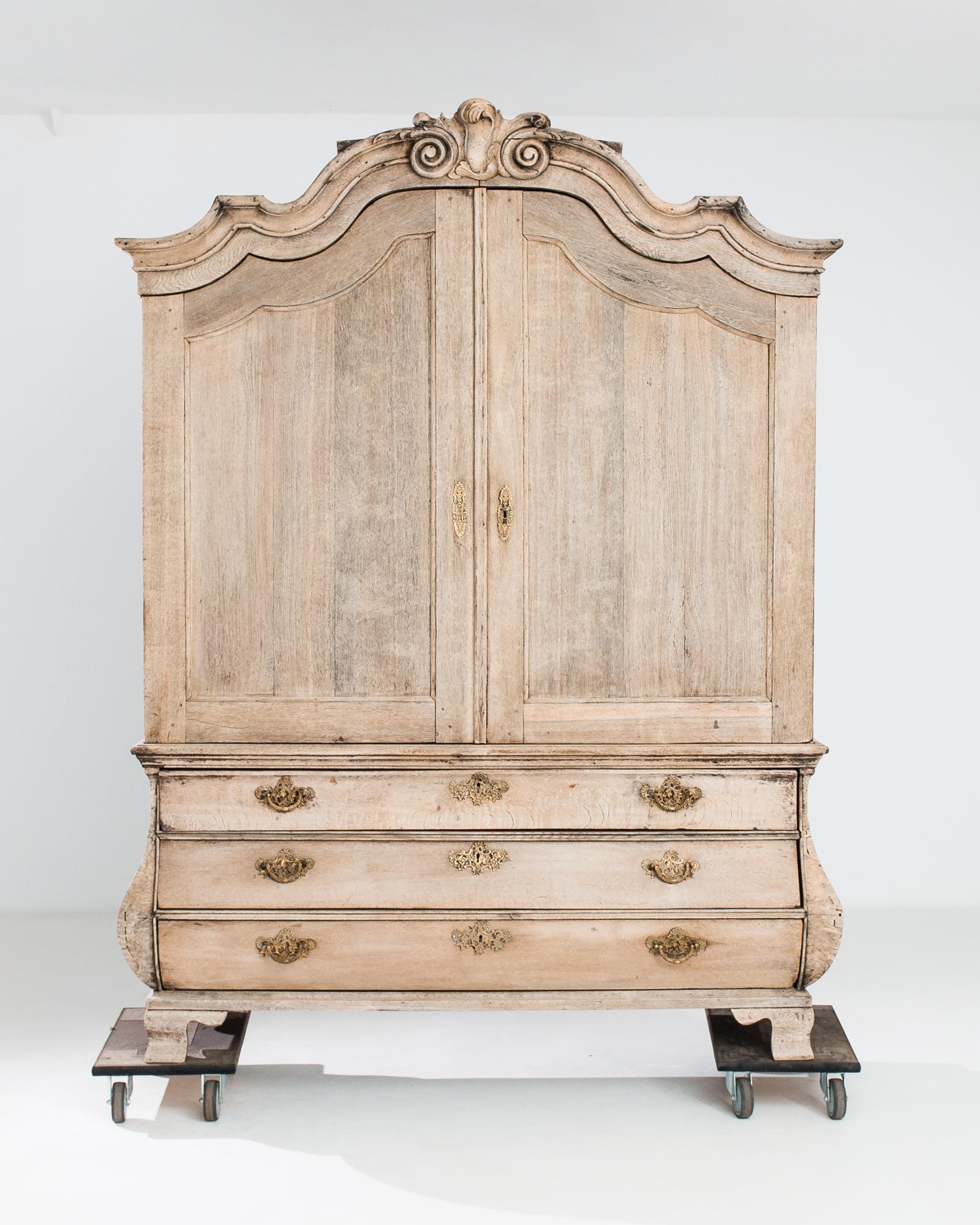 This antique bleached oak cabinet was crafted in the Netherlands, circa 1780. The upper cabinet features four shelves, lodged on a three drawer chest and ogee bracket feet. An arrangement of five hidden drawers allows for discrete closed storage.