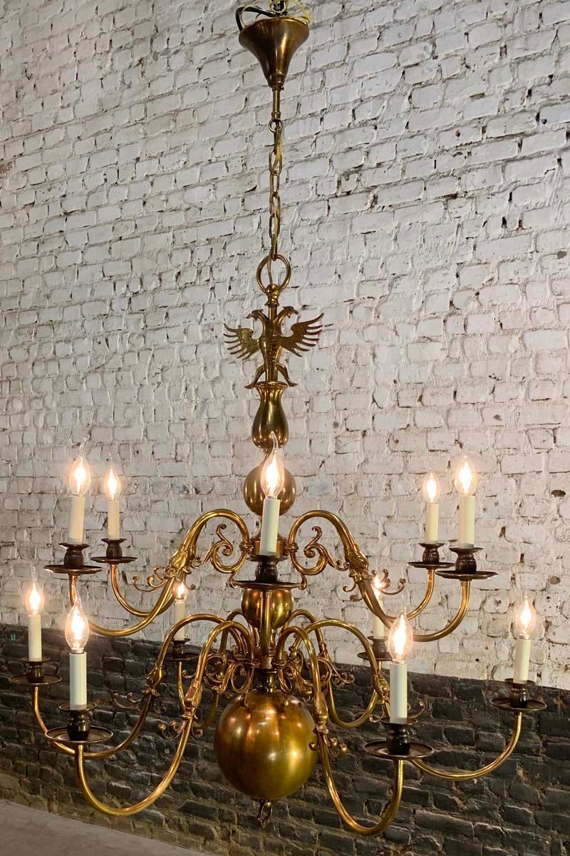 A large twelve-light Baroque style patinated brass Dutch or Flemish chandelier with ball-shaped elements.
All arms depict dolphin’s heads on the midsection. The chandelier ends with a heavy and large globe at the bottom end, that makes the