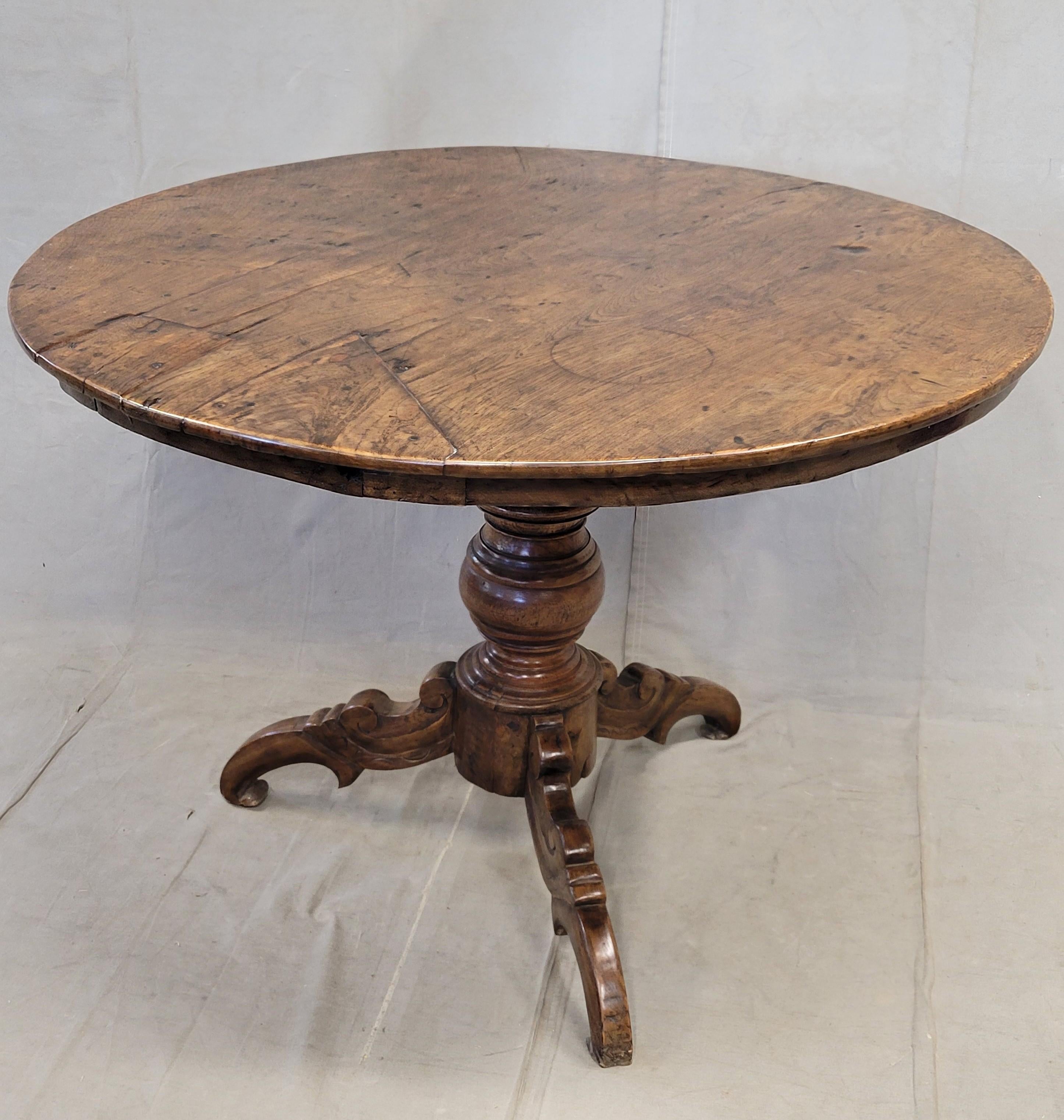 A gorgeous antique 1920s round Dutch Colonial dining table crafted in Java, Indonesia (a Dutch colony until 1945) out of teak. Signs of use and age, including old burns and patches, give this table an lovely amount of rustic character. The teak wood