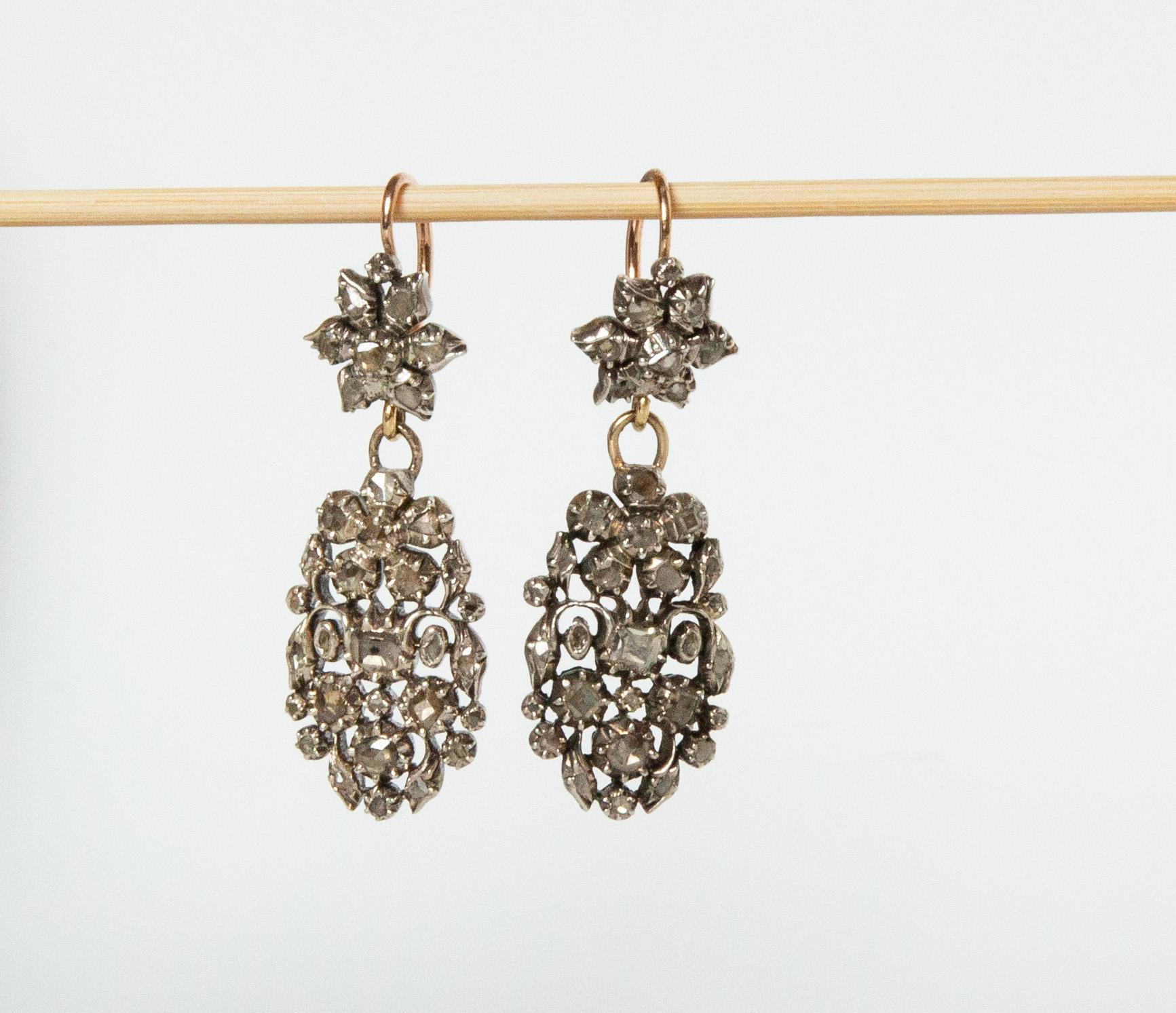 Une paire de boucles d'oreilles pendantes hollandaises (fin du 19e siècle). Les boucles d'oreilles sont en argent et en or (alliage légal inférieur) et présentent un motif floral sous lequel se trouve un ovale serti de diamants taille ancienne et de