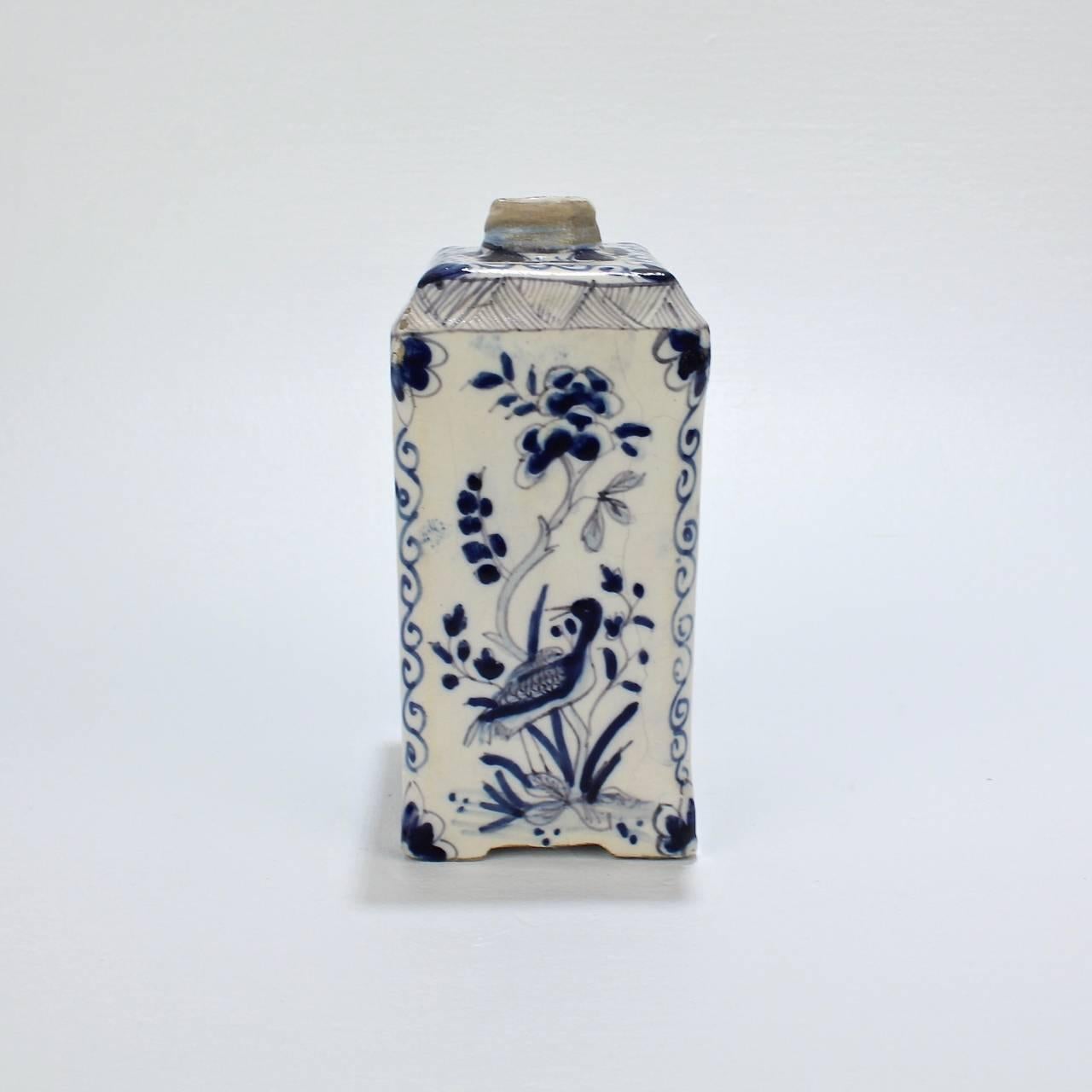 A fine antique Dutch delft tea caddy with a very narrow neck.

The blue and white Chinoiserie decoration depicts Chinese figures, foliage, and birds flanked by chamfered edges with scrollwork and floral devices.

The base bears a blue underglaze