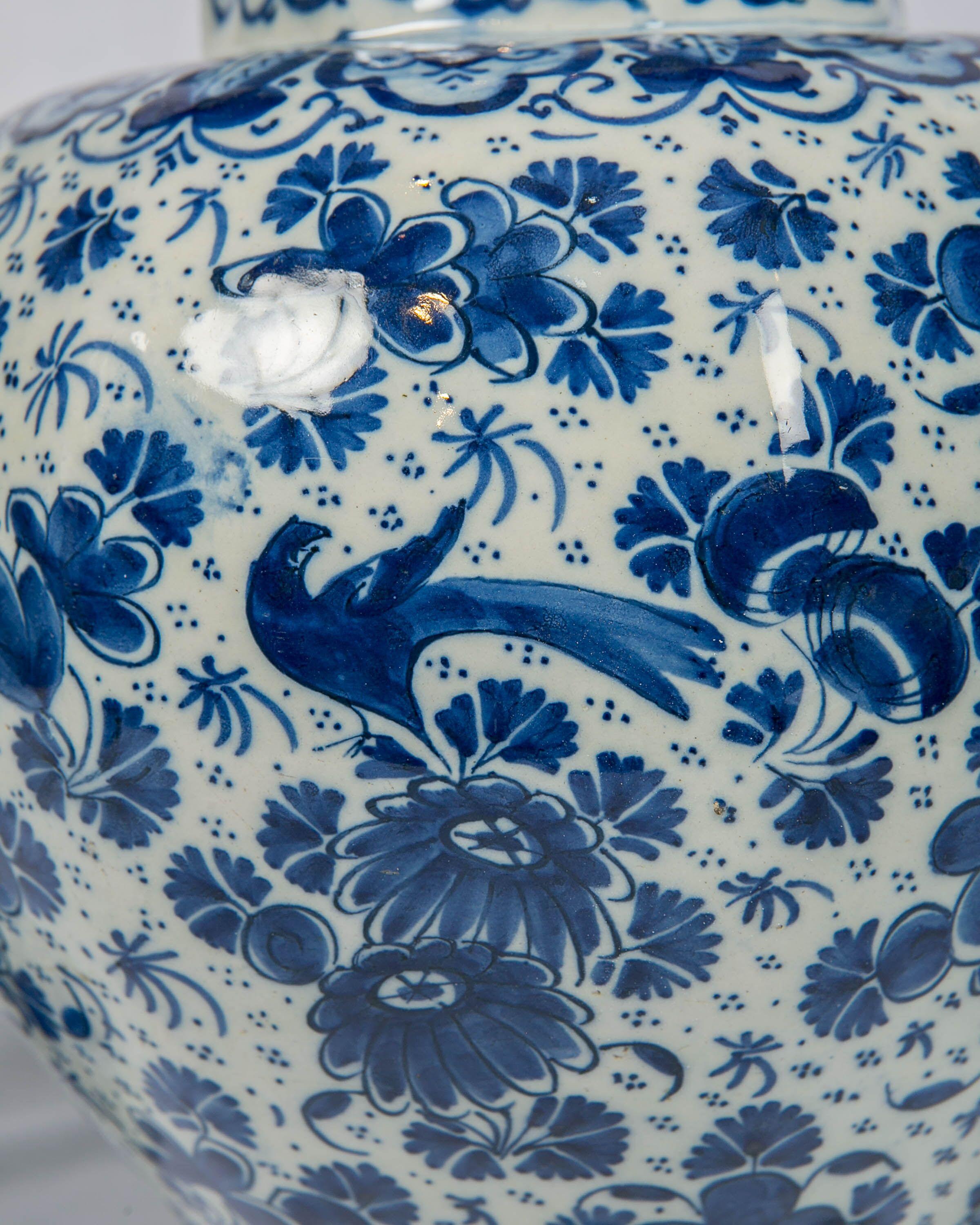 An antique Dutch delft blue and white three-piece garniture consisting of a pair of gourd shaped vases and a single covered vase made circa 1700-1716. This grouping is truly beautiful. All three vases have the mark of Peter Gerritsz. Kam of De Drie