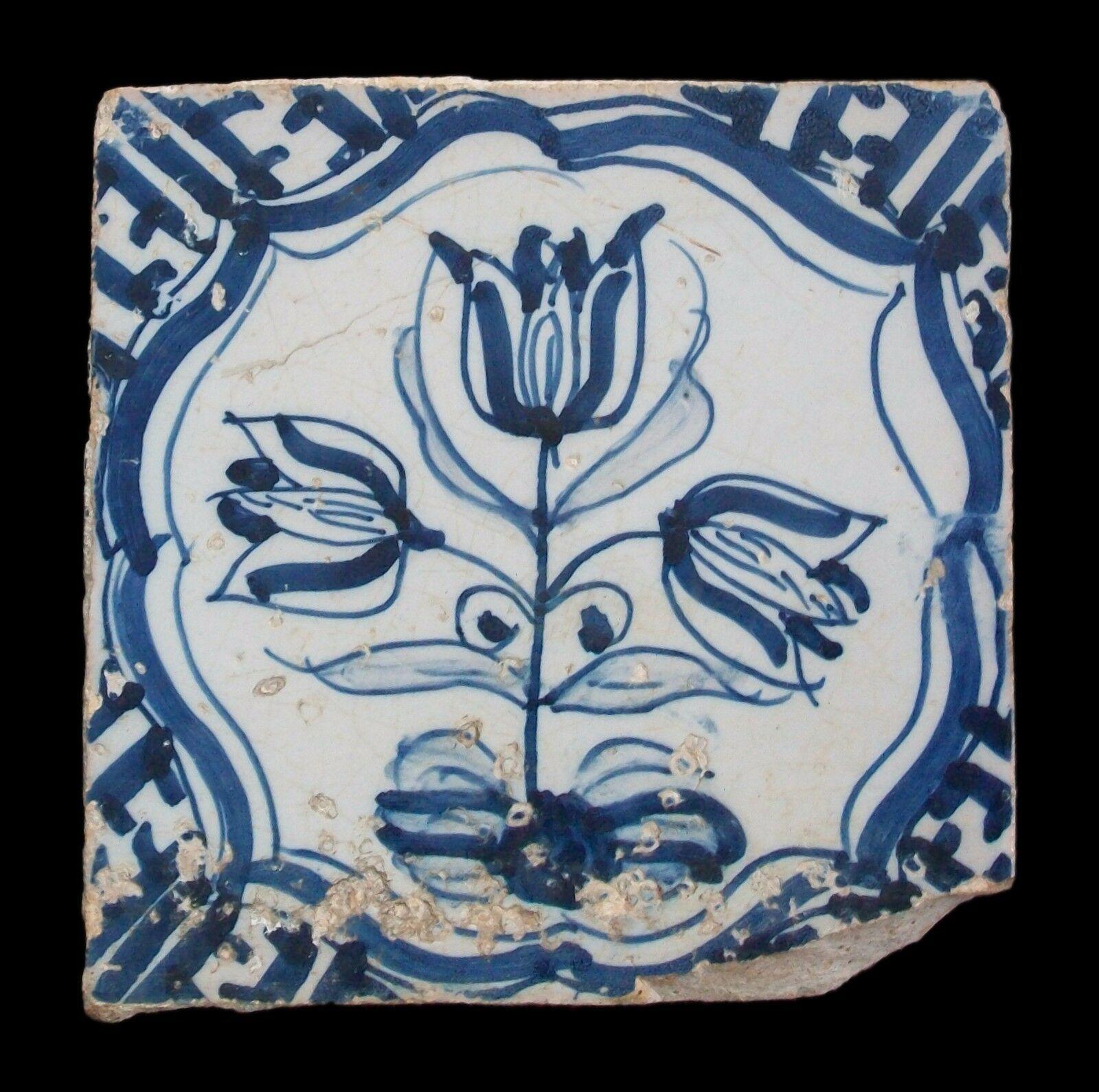Rare antique Dutch Delft ceramic tile - hand painted featuring tulips within a scrolled cartouche - elaborate details to the border - unsigned - Holland - 17th century.

Fair antique condition - loss and glaze chips - damage with old firing crack