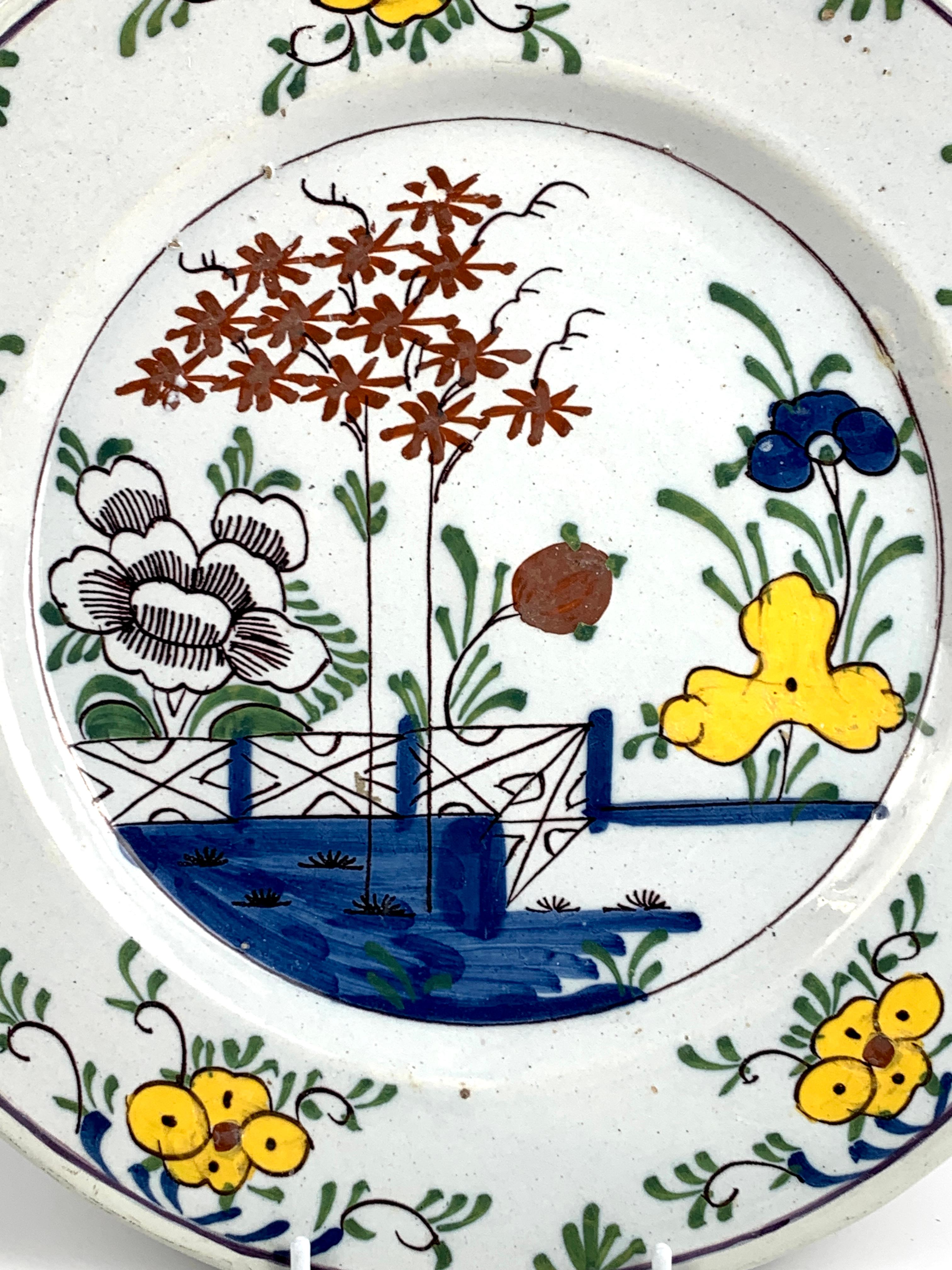 Chinoiserie blue water in the foreground 
This Dutch Delft charger features a hand painted garden scene with large bright yellow flowers, green leaves, small iron red plum blossom flowers, and touches of cobalt blue.
The decoration is simple and