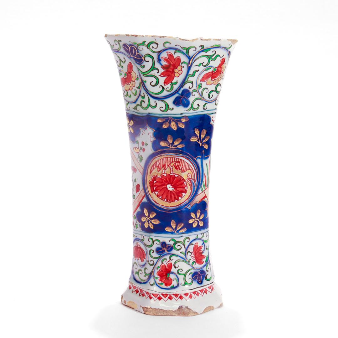 Vase en forme de gobelet en poterie hollandaise de Delft.

Par Pieter Adriaensz Kocx de De Grieksche A.

Sur fond blanc, décorée de motifs floraux rouges, bleus et verts, avec des accents dorés sur l'ensemble. 

Marqué à la base avec la marque de
