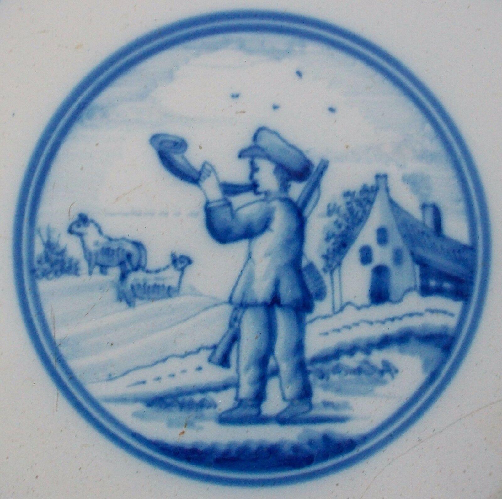Rare antique Dutch Delft ceramic tile - hand painted featuring a shepherd and sheep in a pastoral setting within a round cartouche - 'spiderweb' pattern to the corners - unsigned - Holland - 18th century.

Fair antique condition - loss - damage