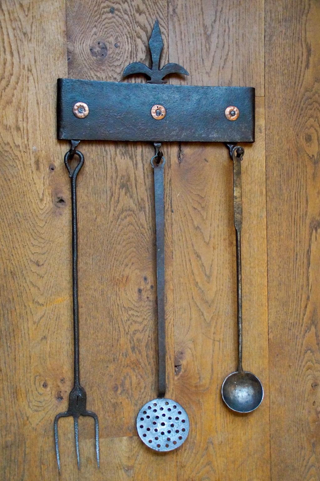 17th century Dutch Louis XIV fireplace tool set consisting of a hanger and three fire irons and kitchen tools. From left to right is included a wrought iron toasting fork, a wrought iron skimmer and a wrought iron ladle. The tool set is in a good