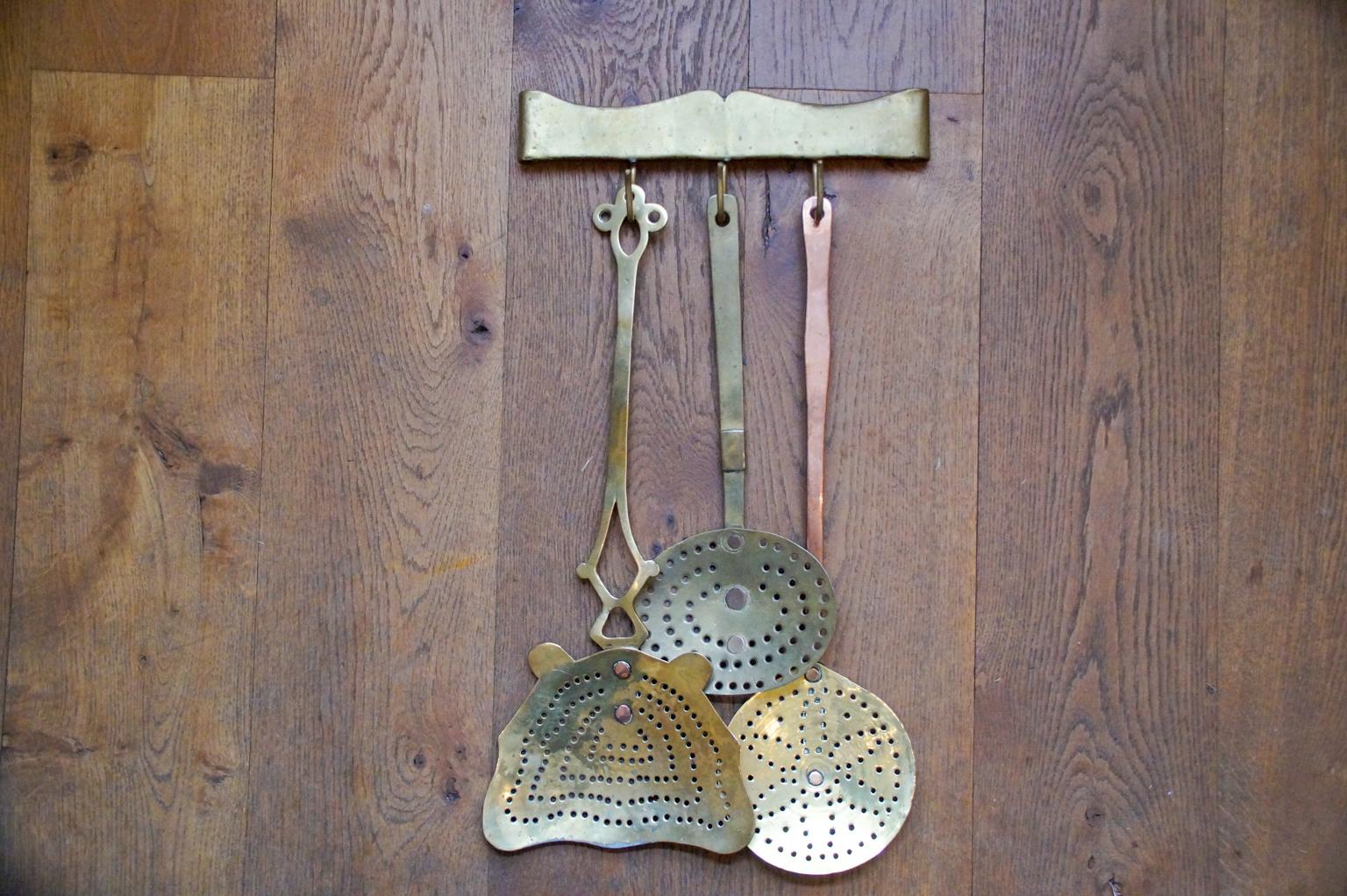 18th-19th century Dutch Louis XV fireplace tool set consisting of a hanger and three different skimmers. Two skimmers are made of brass entirely and one skimmer is made of brass with a copper handle. The tool set is in a good condition and is fully