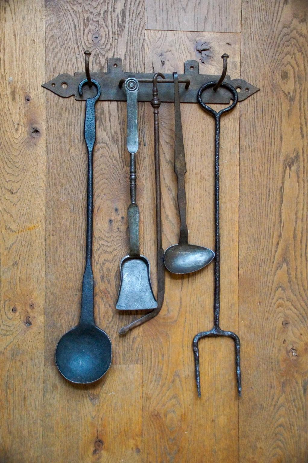 18th-19th century Dutch Louis XV fireplace tool set consisting of a hanger and five fire irons and kitchen tools. From left to right is included a wrought iron spoon, a wrought iron small shovel, a wrought iron poker, a wrought spoon, and a wrought