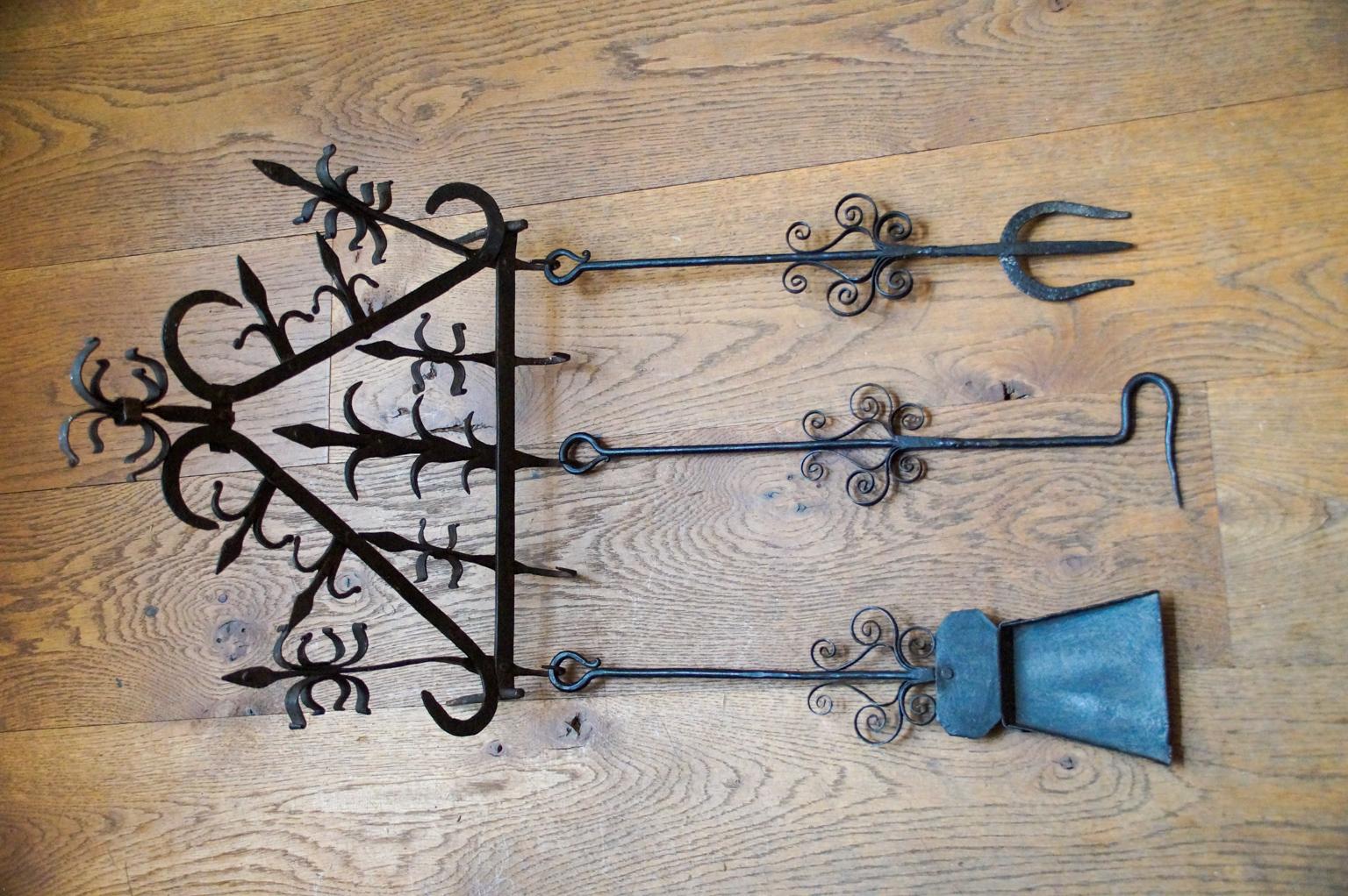 18th-19th century Dutch Louis XV fireplace tool set consisting of a hanger and three fire irons and kitchen tools. From left to right is included a wrought shovel, a wrought iron poker, and a wrought toasting fork. The tool set is in a good