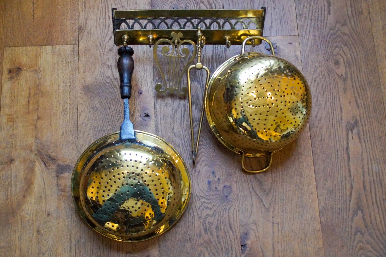 Beautiful 18th-19th century Dutch Louis XV fireplace tool set consisting of a hanger and four fire irons and kitchen tools. From left to right is included a brass strainer with a wrought iron and wooden handle, a brass trivet, brass tongs, and a