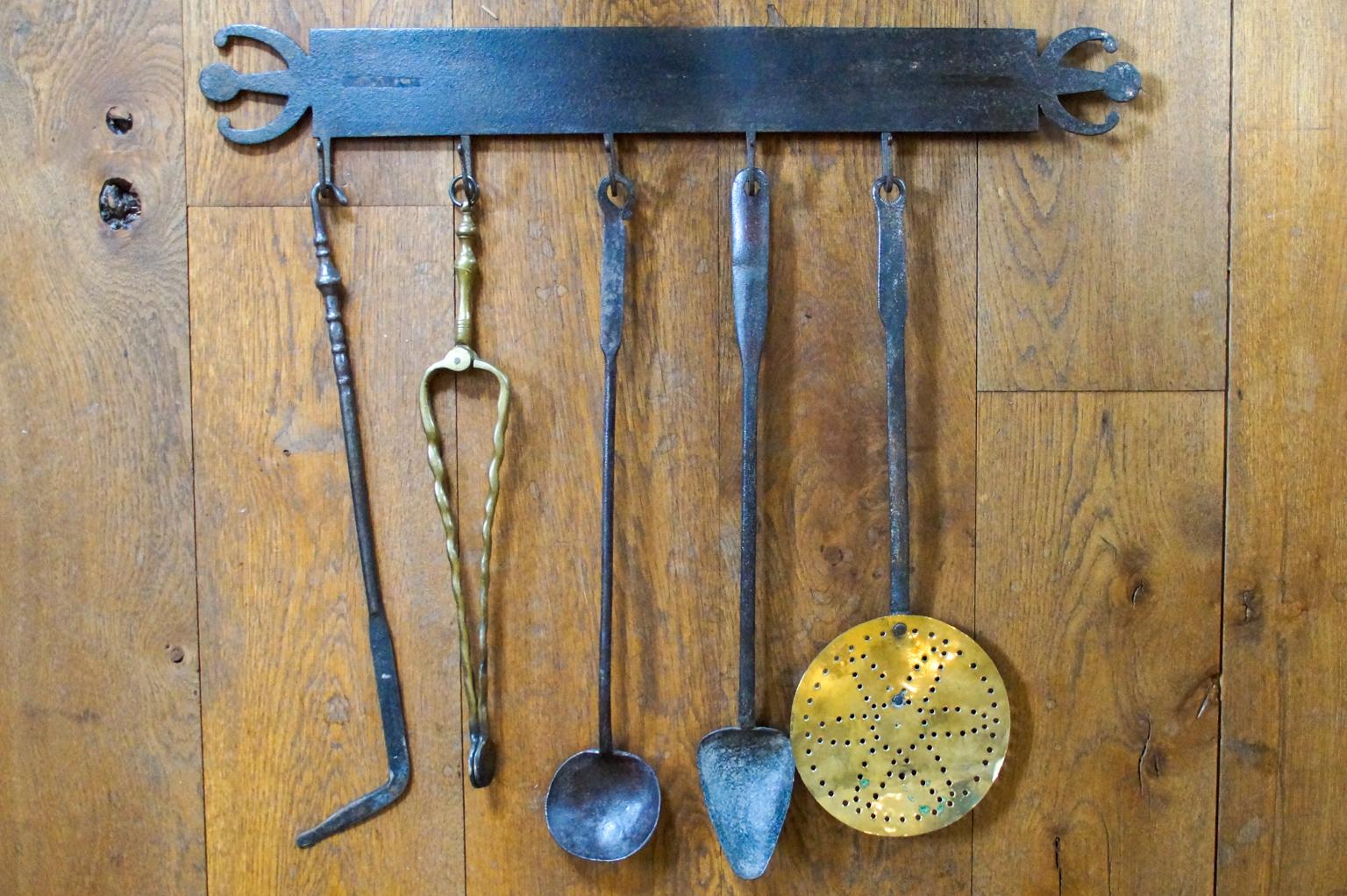 18th or early 19th century Dutch Louis XV fireplace tool set consisting of a hanger and five fire irons and kitchen tools. The tools include a wrought iron poker, brass tongs, two wrought spoons and a wrought iron with brass skimmer. The tool set is