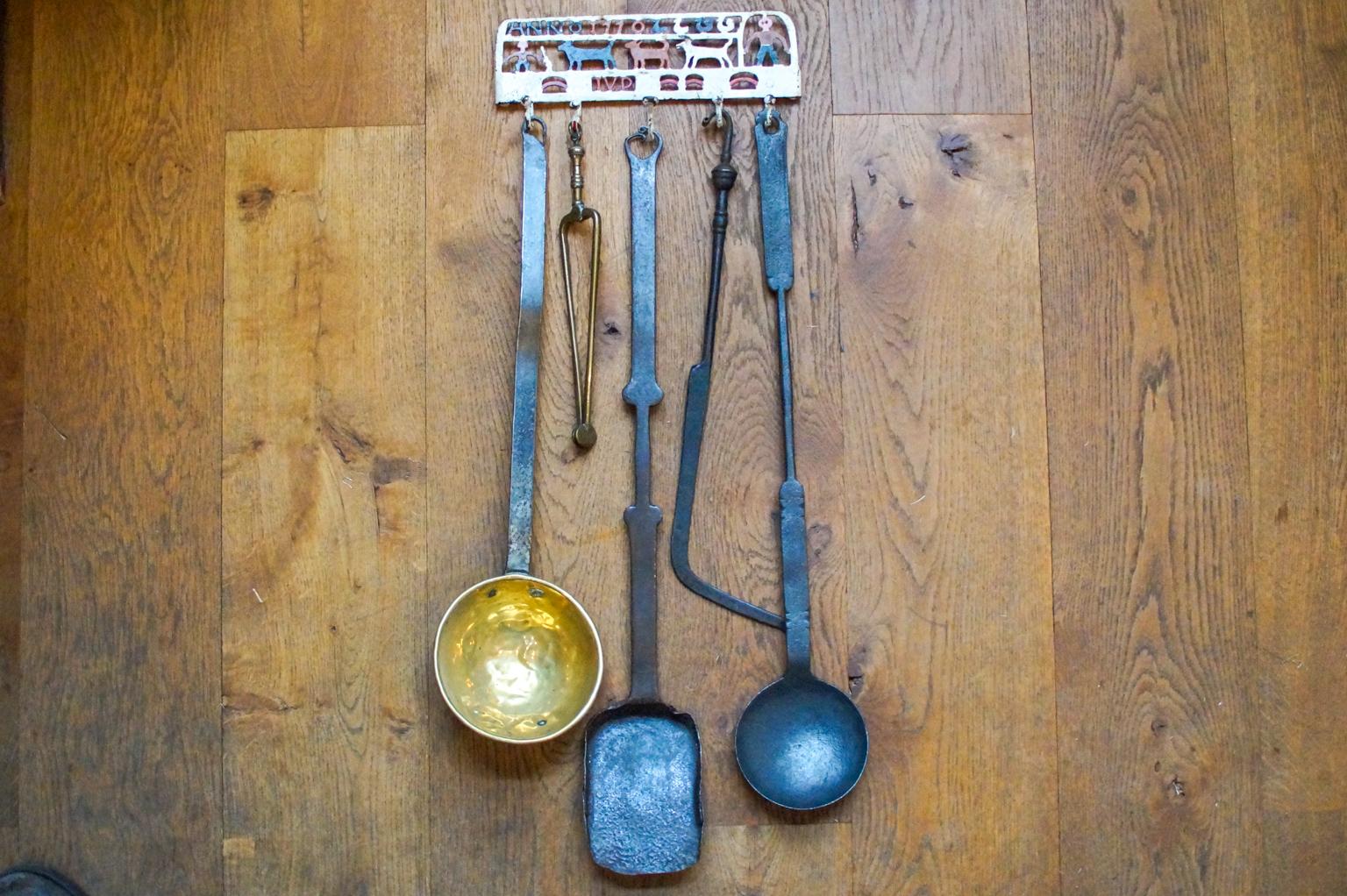 18th century Dutch Louis XV fireplace tool set consisting of a hanger and five fire irons and kitchen tools. From left to right is included a brass ladle with a wrought iron handle, brass tongs, a wrought iron small shovel, a wrought iron poker and