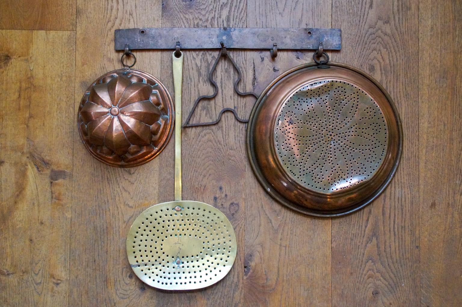 19th century Dutch Napoleon III fireplace tool set consisting of a hanger and four different kitchen tools. From left to right the kitchen tools include a copper with wrought iron baking tin, a brass skimmer, a wrought iron trivet, and a copper with