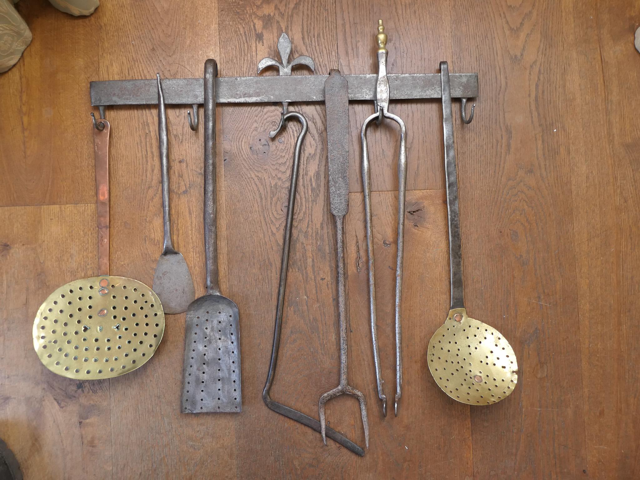 Ensemble d'outils de cheminée Louis XV hollandais du XVIIIe siècle comprenant un cintre et sept fers à repasser et ustensiles de cuisine. De gauche à droite, on trouve une louche en laiton avec un manche en cuivre, une spatule en fer forgé, une
